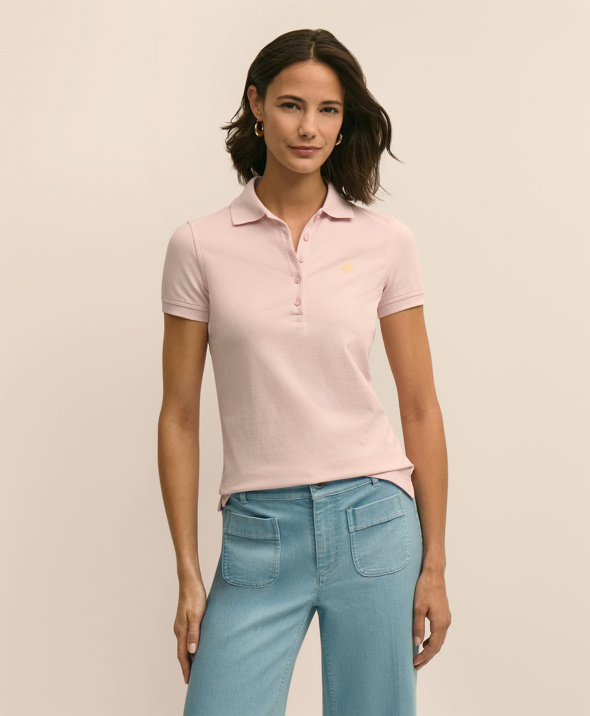 Woman wearing a light pink polo shirt and blue jeans