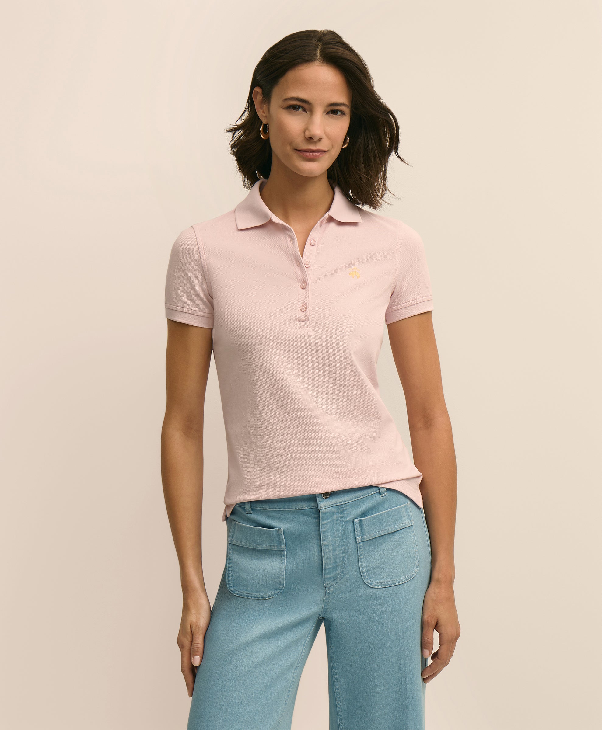 Woman wearing a light pink polo shirt and blue jeans