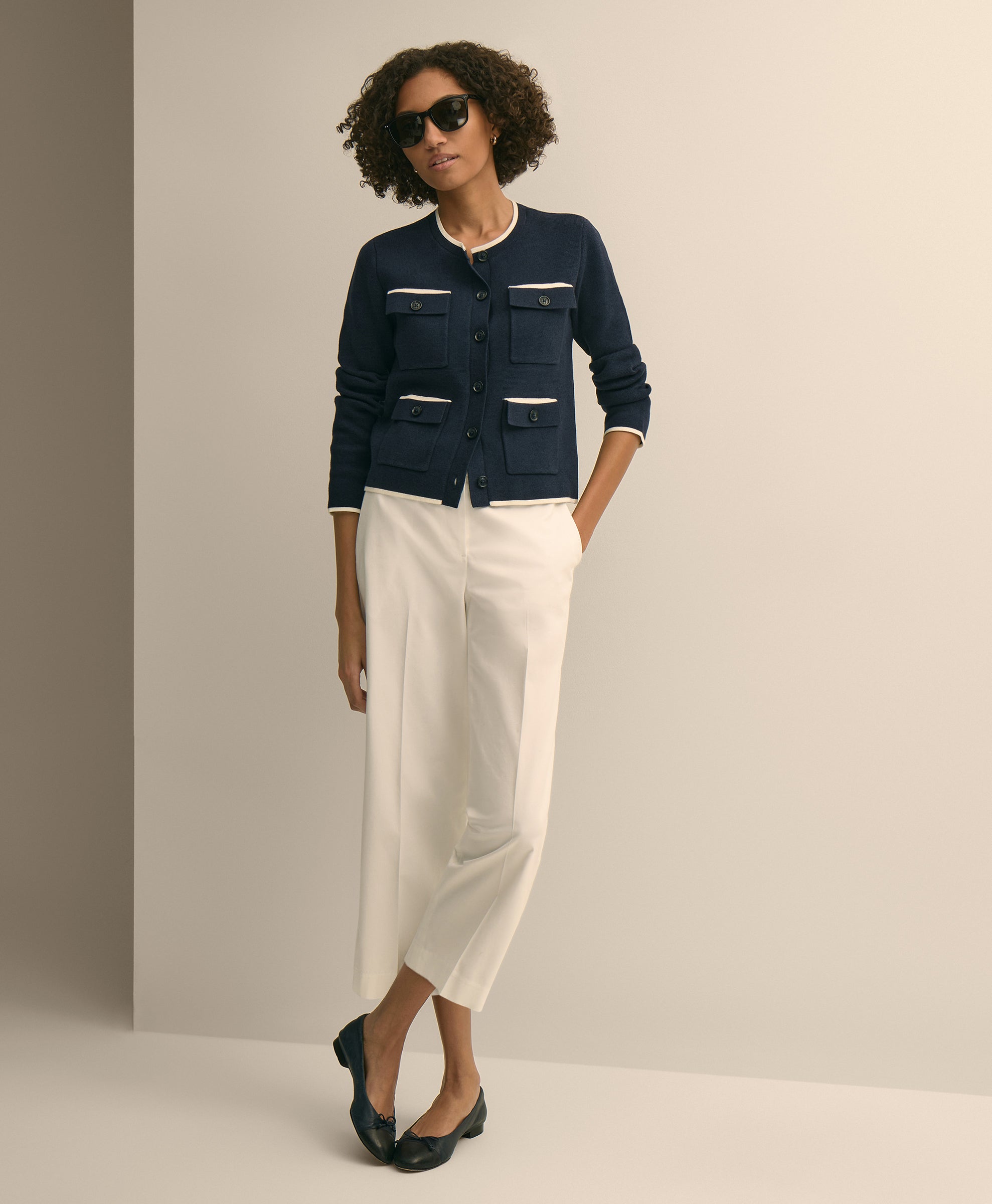 Woman wearing a navy jacket with white accents and white pants