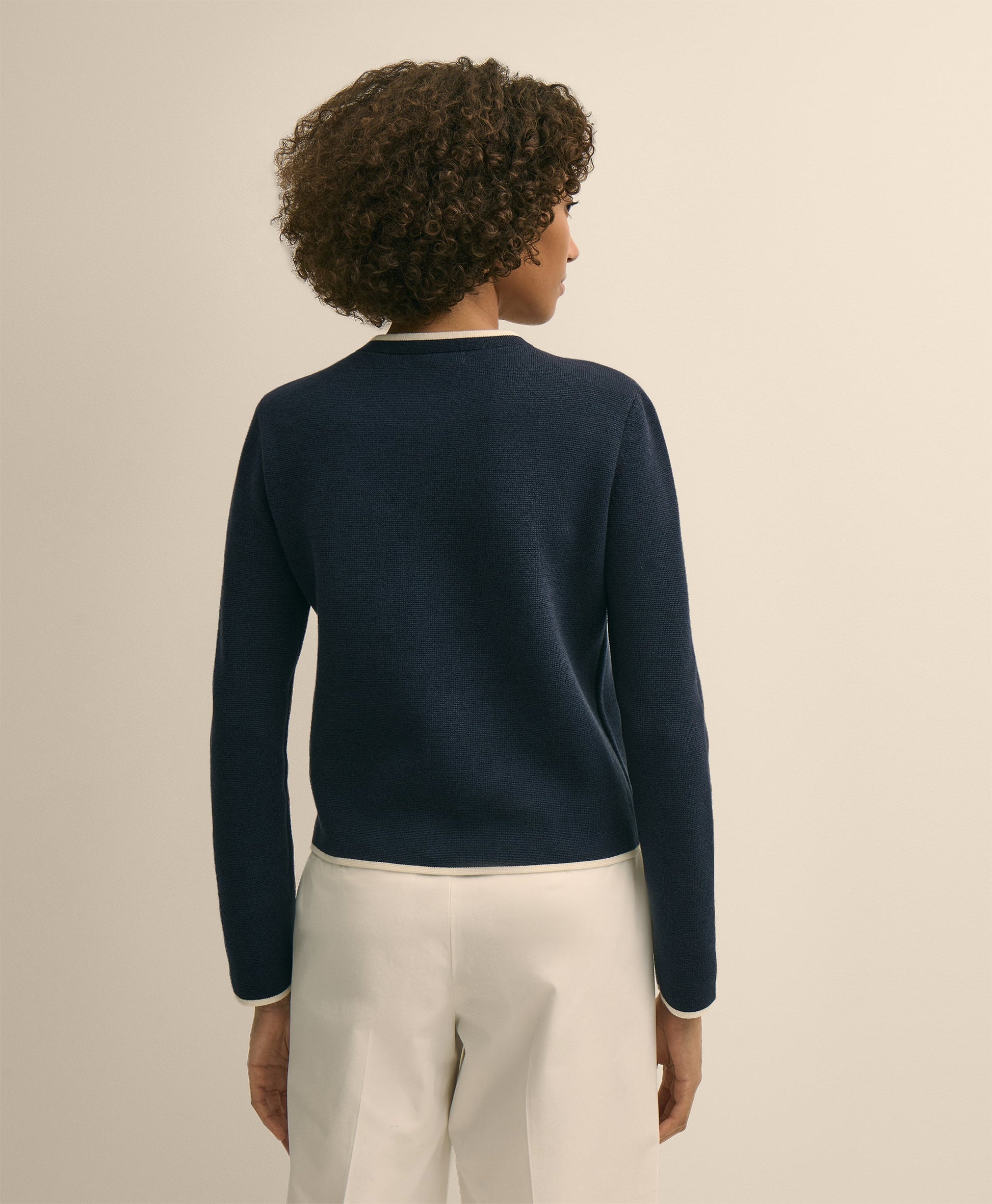 Person wearing a navy sweater and light-colored pants