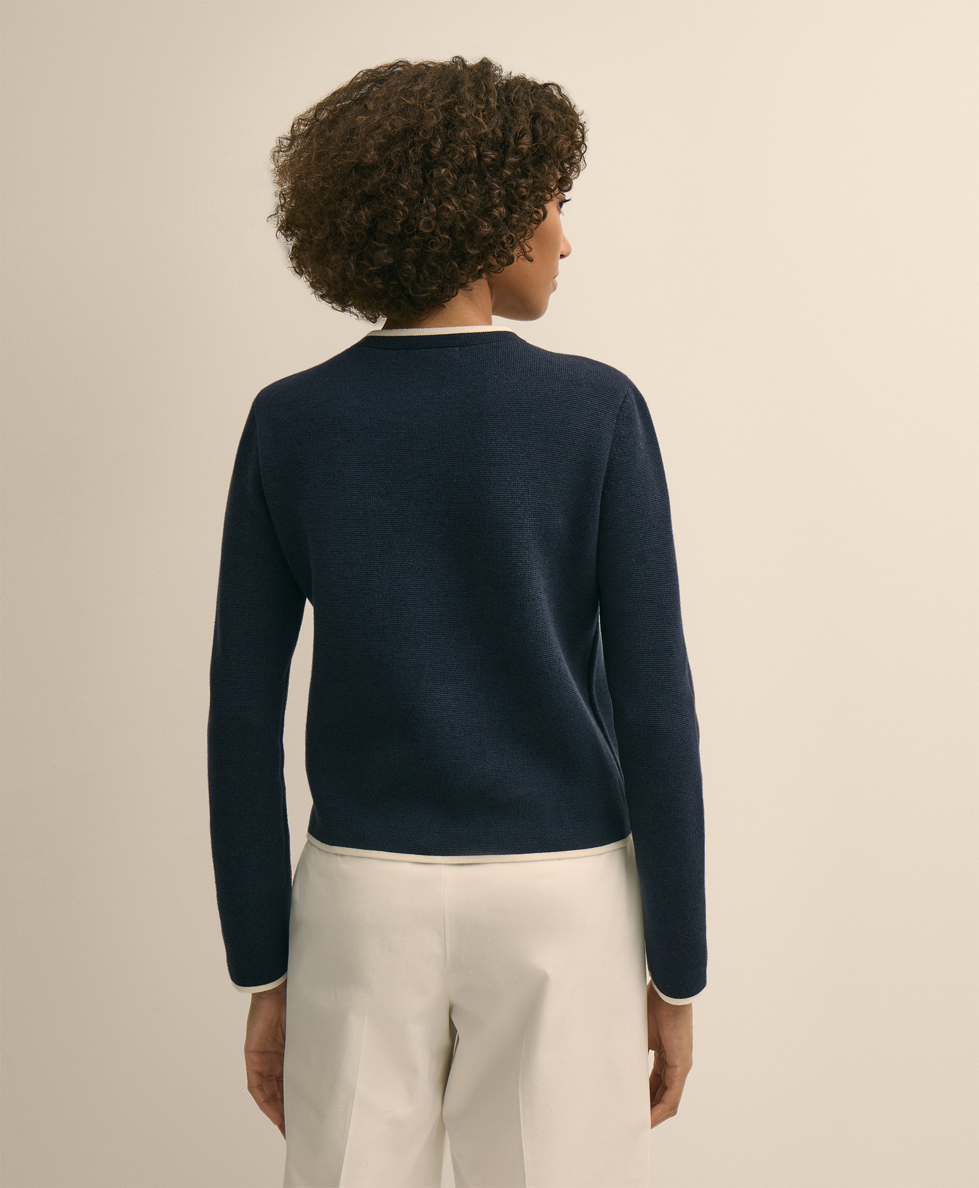 Person wearing a navy sweater and light-colored pants