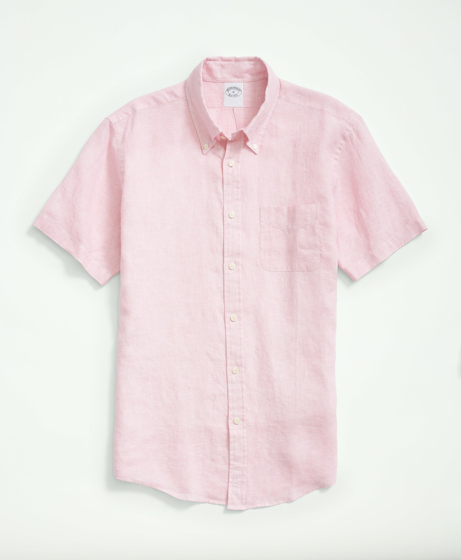 Portrait view of a man in a pink fish print shirt, paired with navy trousers.