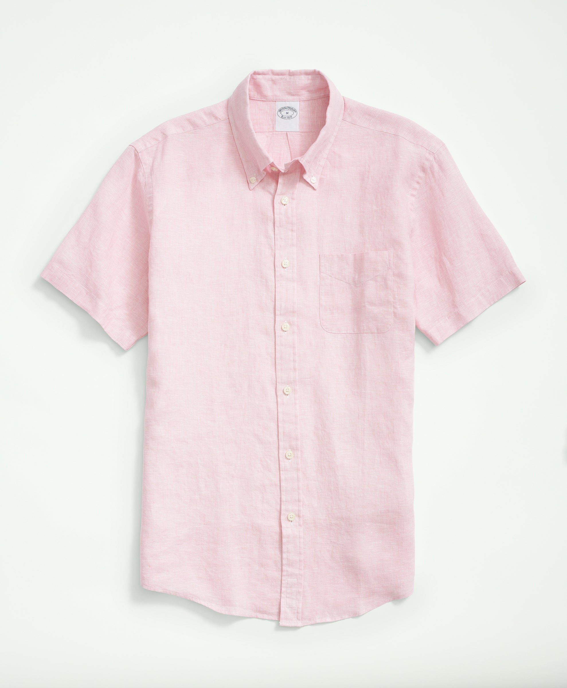 Portrait view of a man in a pink fish print shirt, paired with navy trousers.