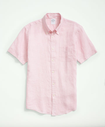 Portrait view of a man in a pink fish print shirt, paired with navy trousers.