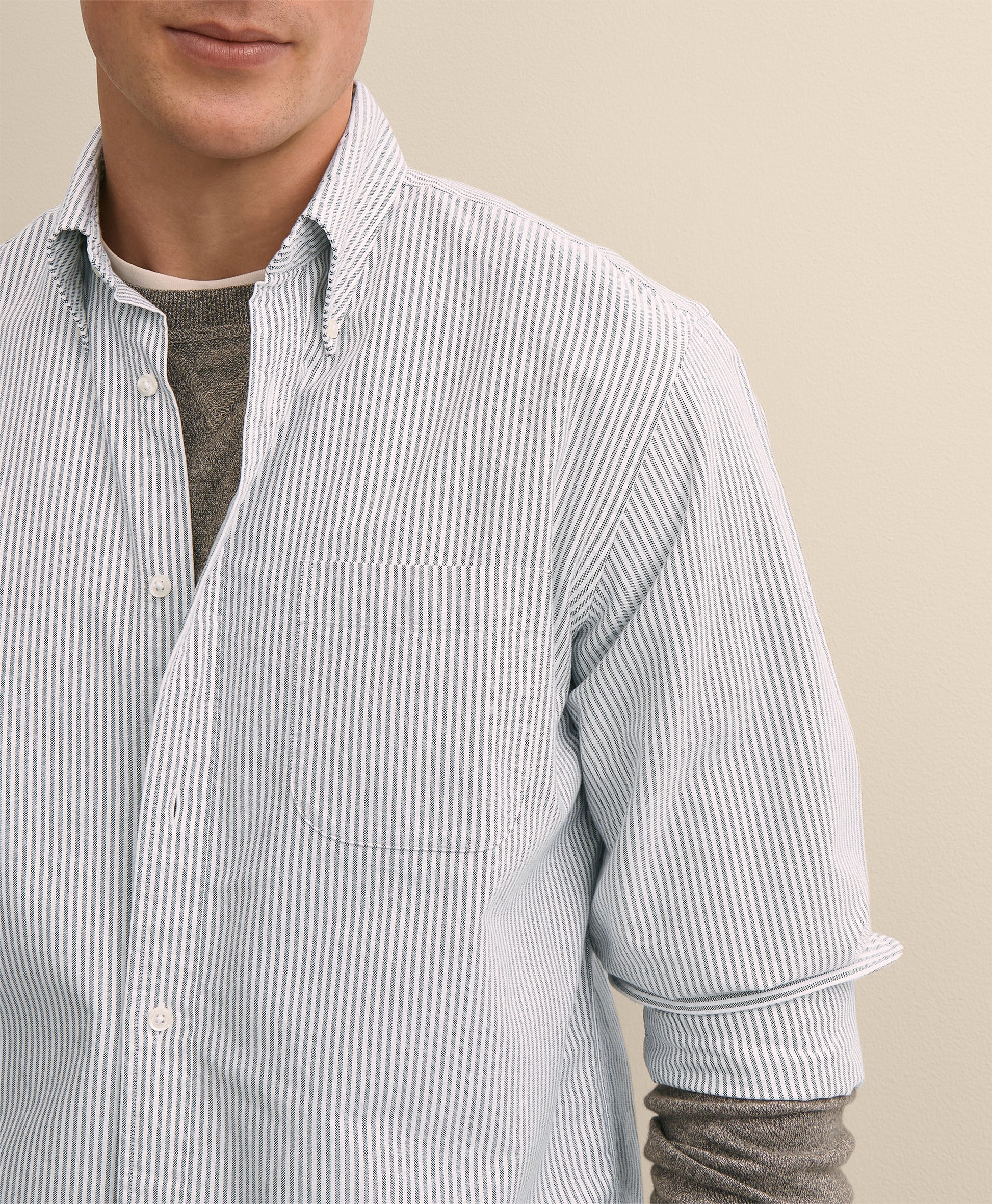 Man wearing a light blue striped shirt with rolled-up sleeves
