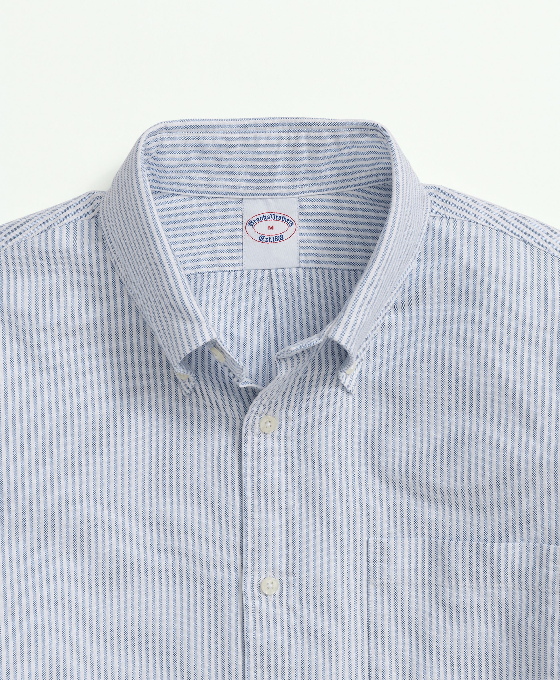 Close-up of a light blue and white striped shirt with a collar on a light gray background