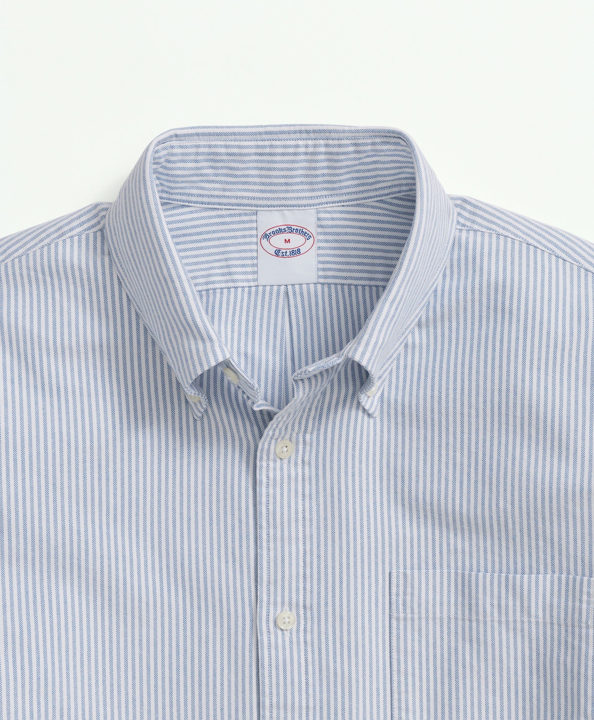 Close-up of a light blue and white striped shirt with a collar on a light gray background