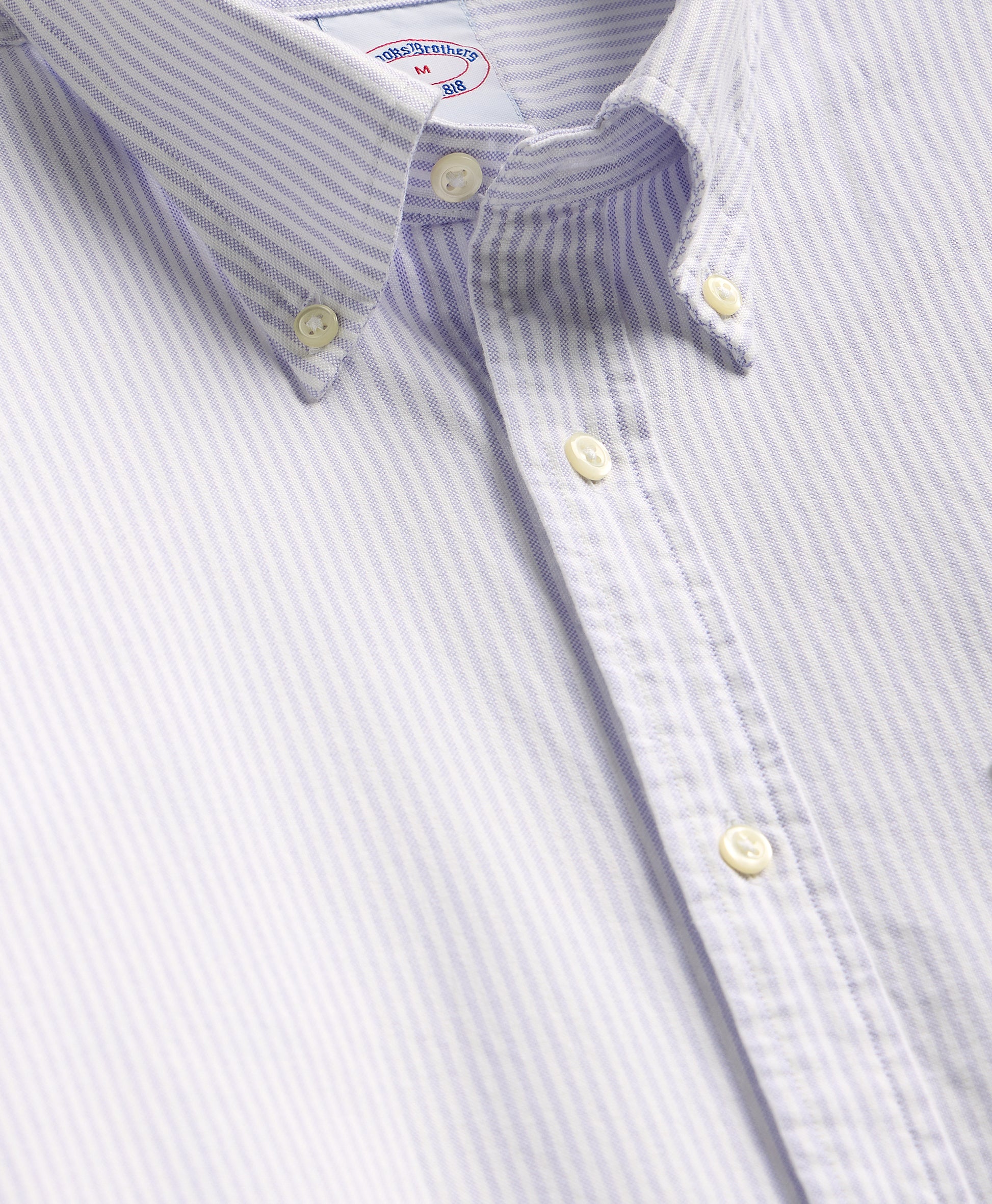 Close-up of a striped shirt with button details on a light gray background