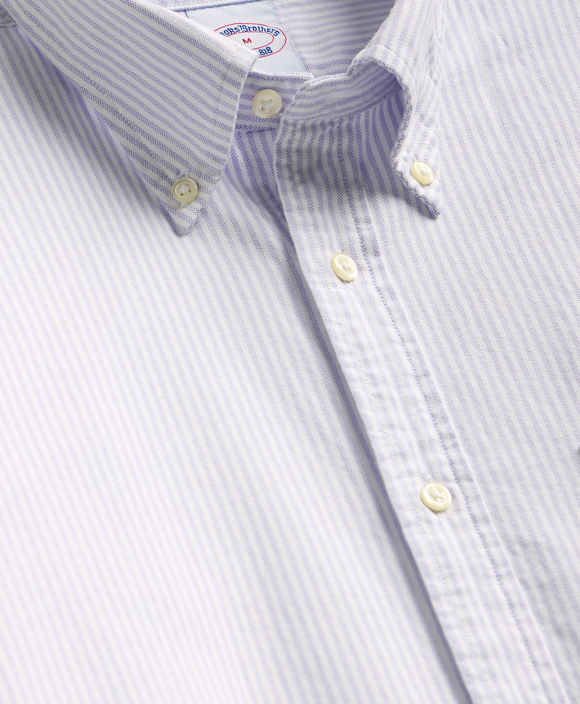Close-up of a striped shirt with button details on a light gray background