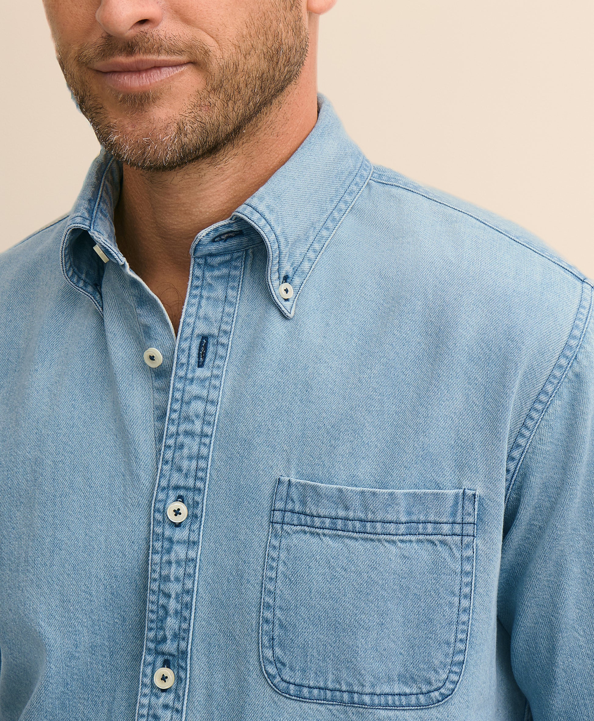 Close-up of a man wearing a light blue denim shirt