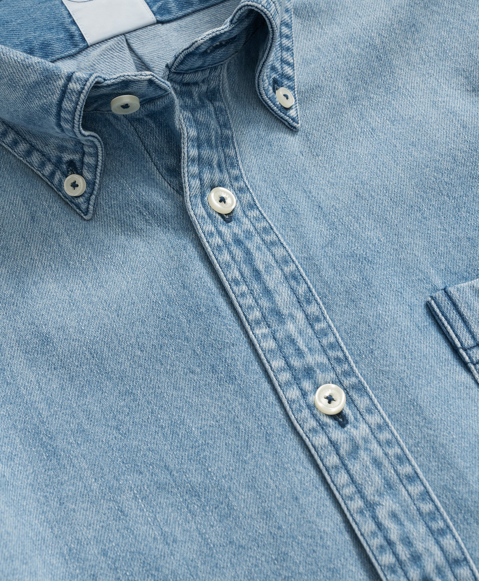 Close-up of a light blue denim shirt with collar and buttons.