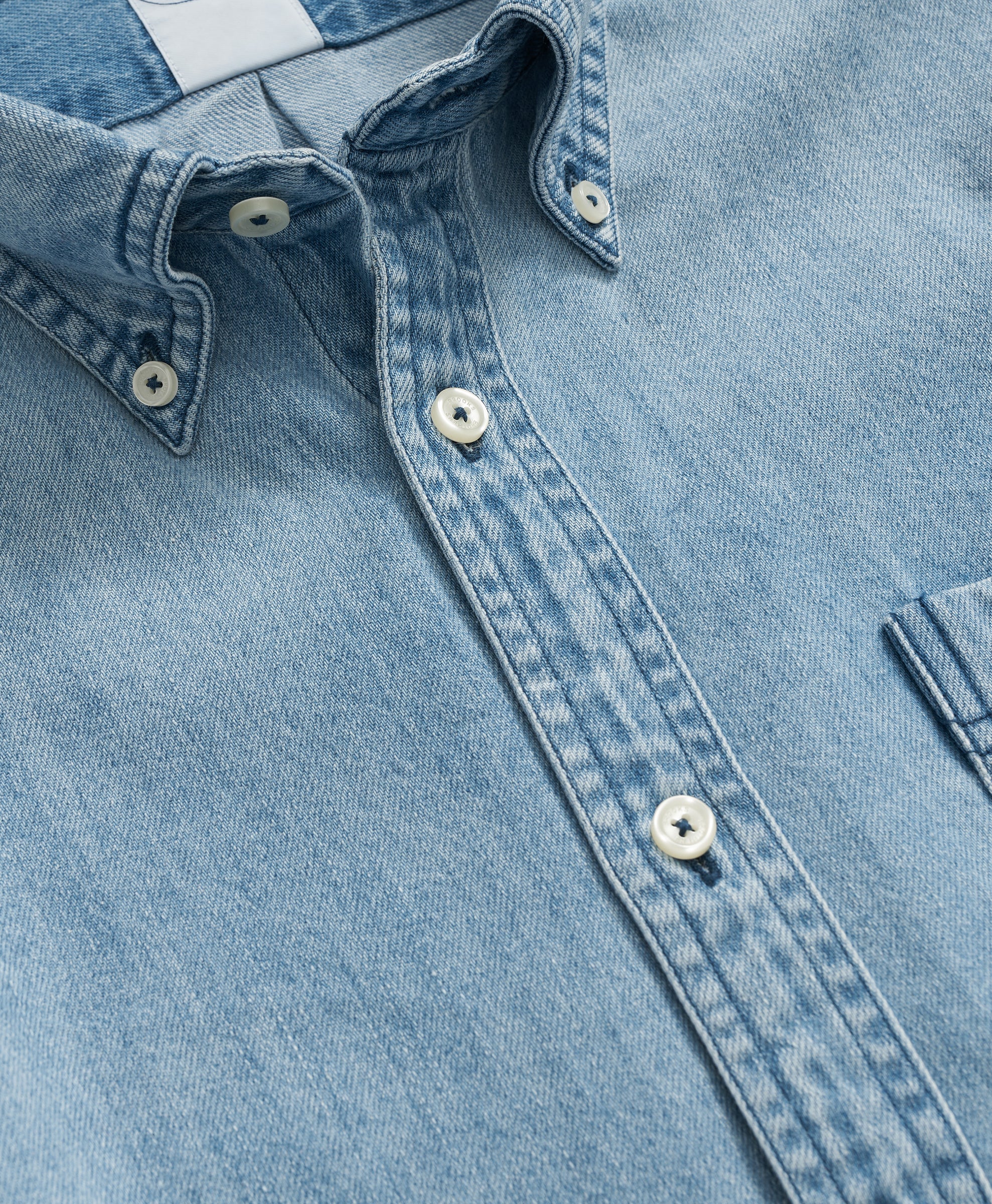 Close-up of a light blue denim shirt with collar and buttons.