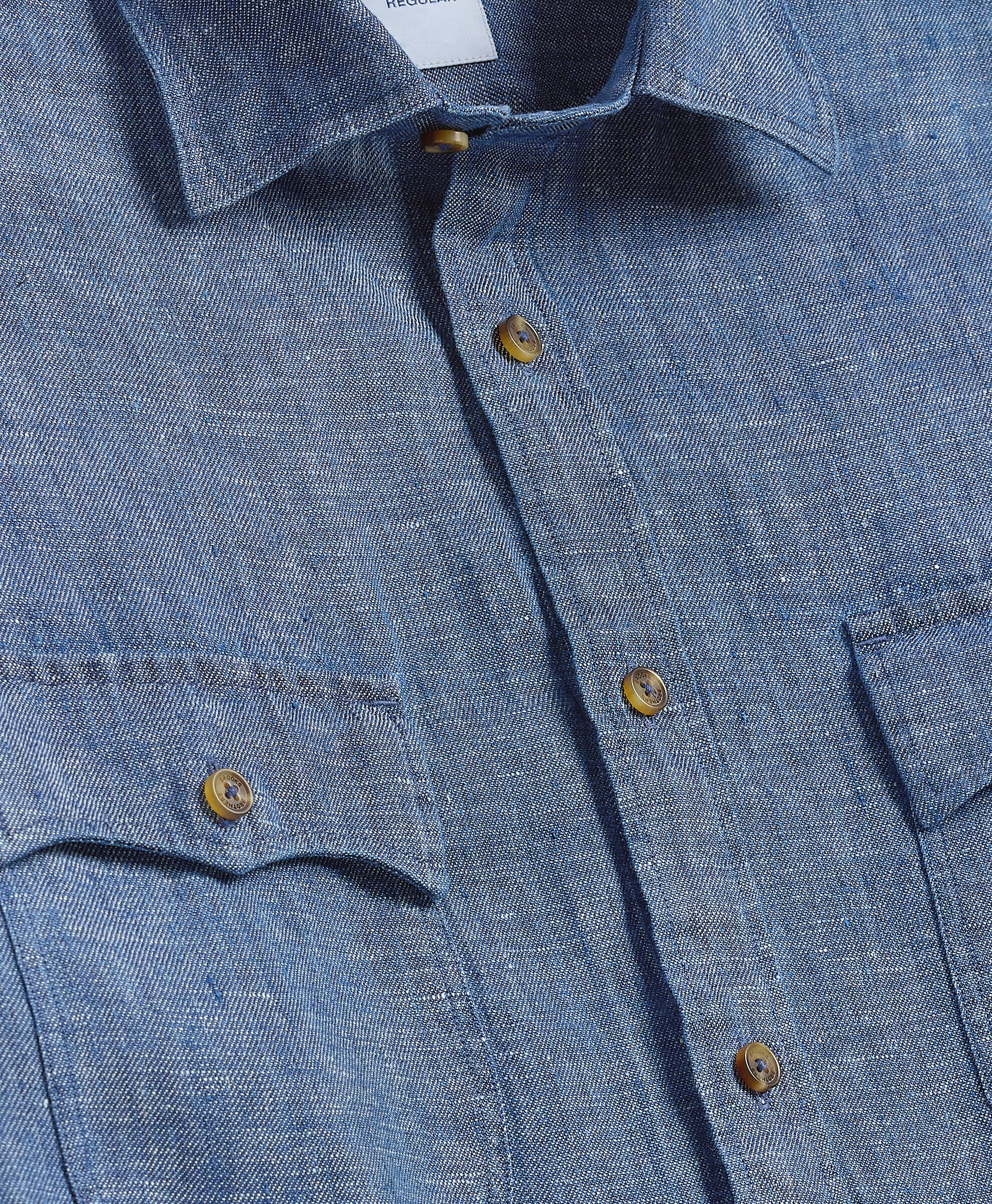 Close-up of a blue denim shirt with buttons and a collar.