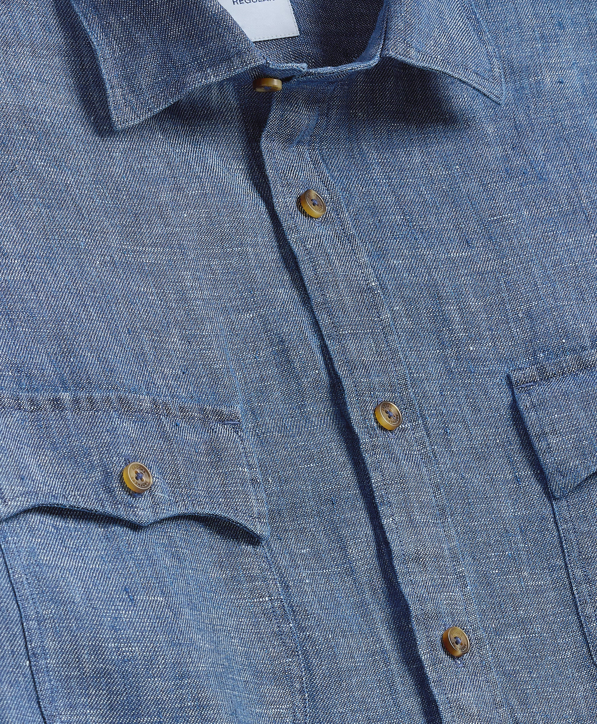 Close-up of a blue denim shirt with buttons and a collar.