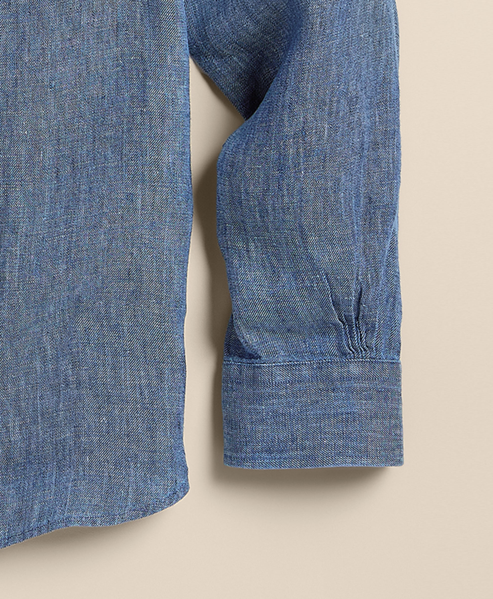 Close-up of a blue denim shirt with rolled-up sleeve