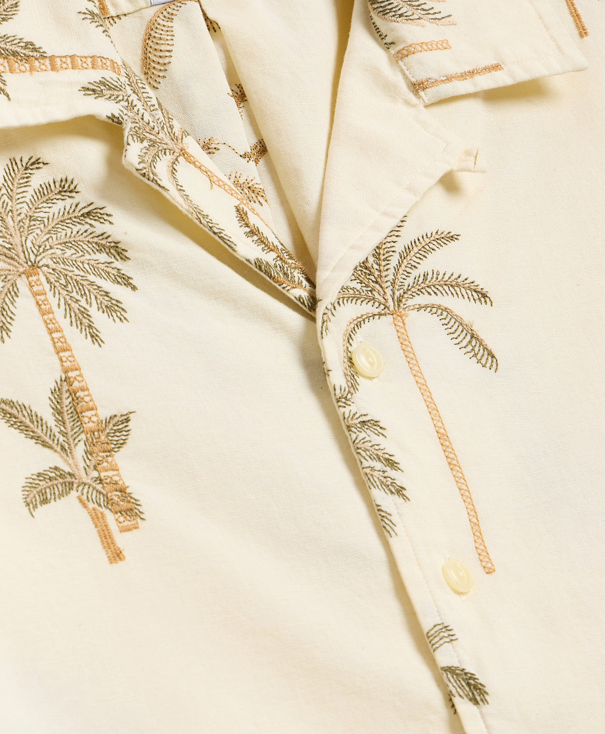 Close-up texture of cream cotton fabric with detailed blue and yellow fish print.