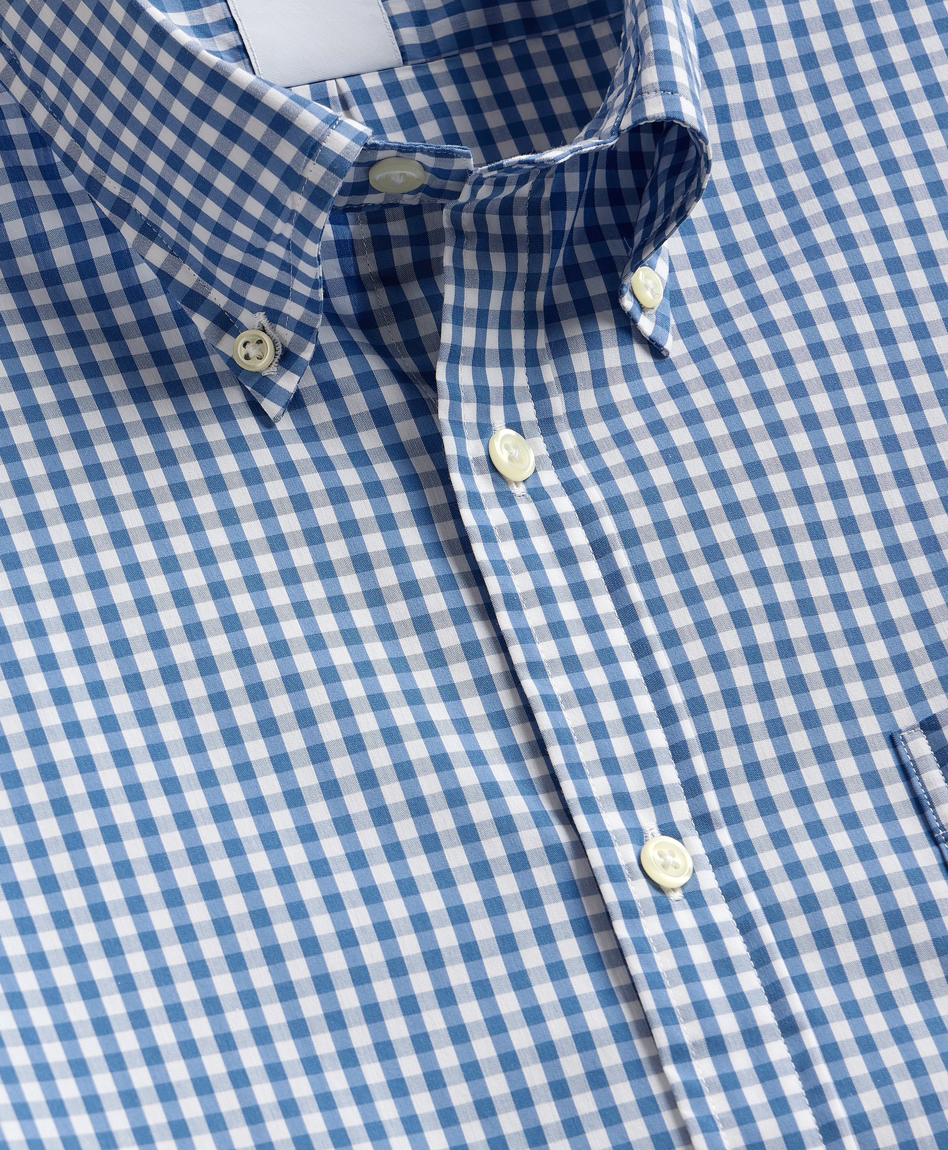 Close-up of a blue and white checkered shirt with buttons.