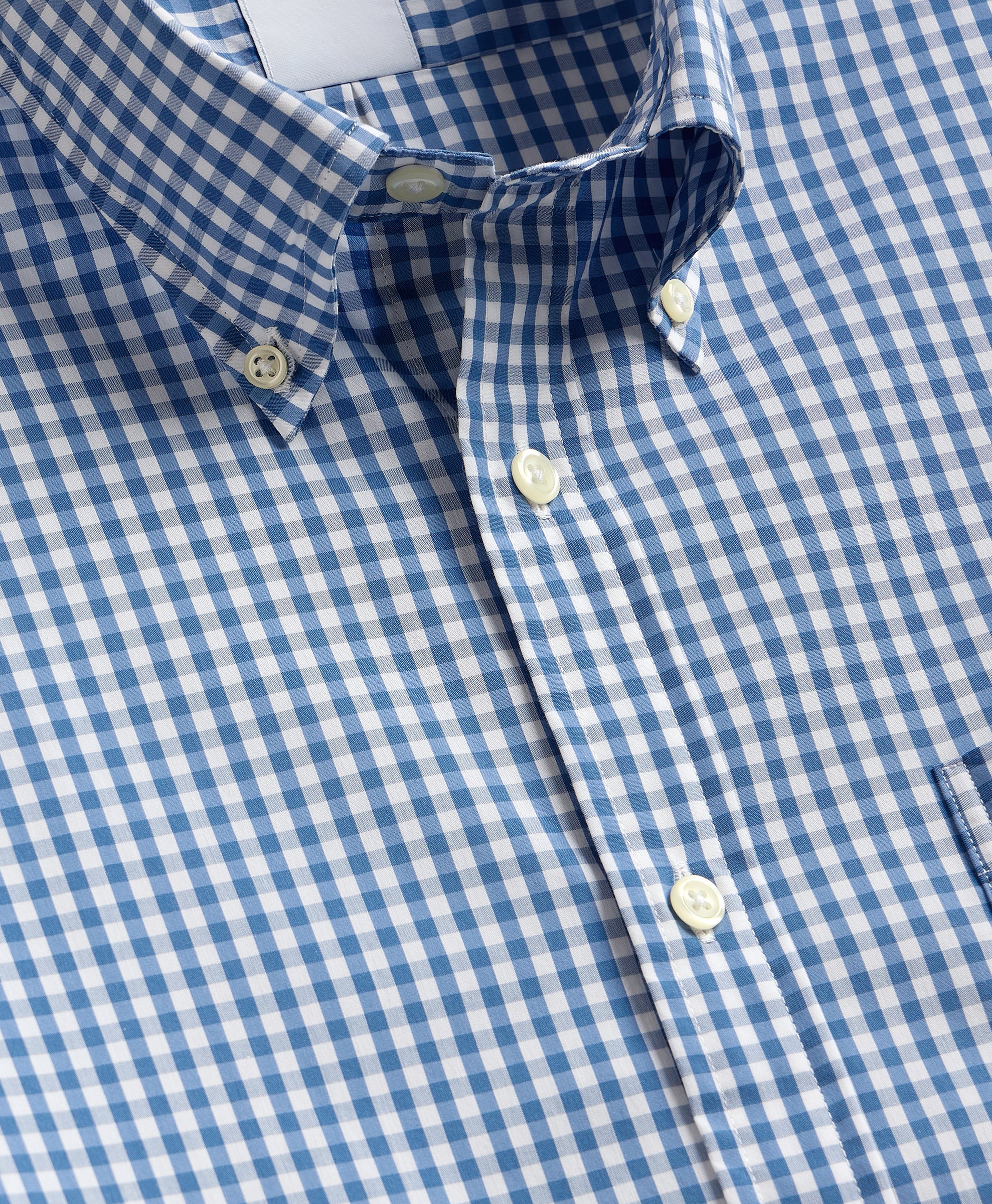 Close-up of a blue and white checkered shirt with buttons.