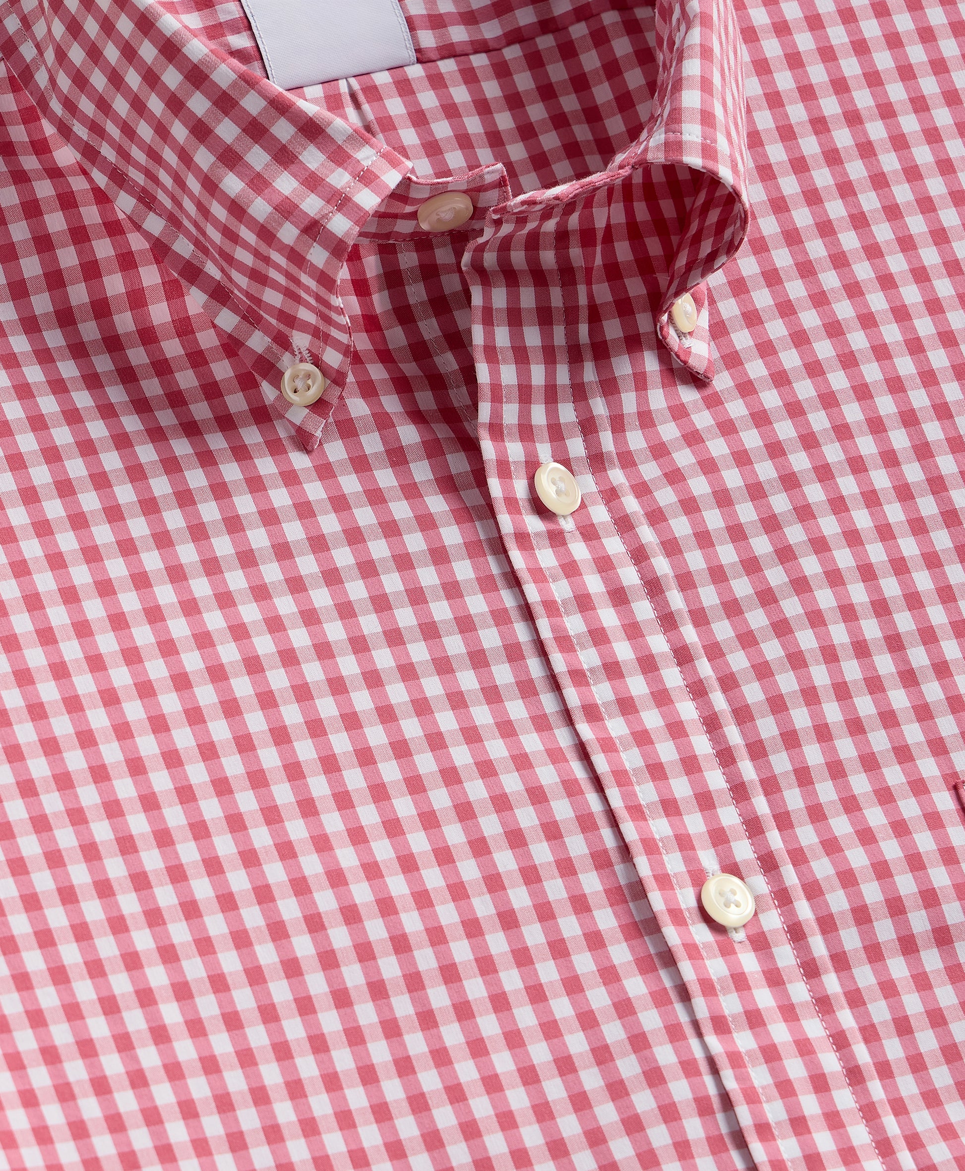 Close-up of a red and white checkered shirt with buttons.