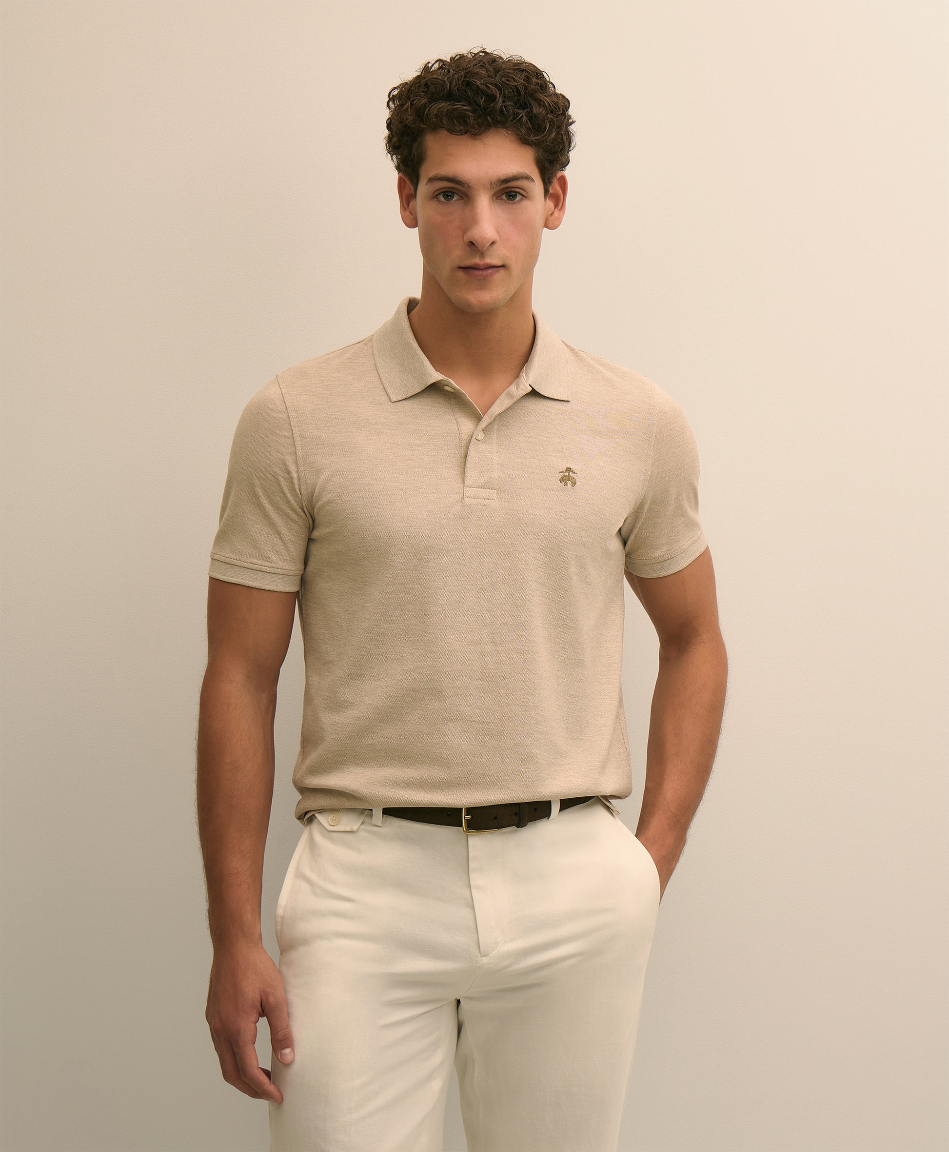Man wearing a beige polo shirt and white pants