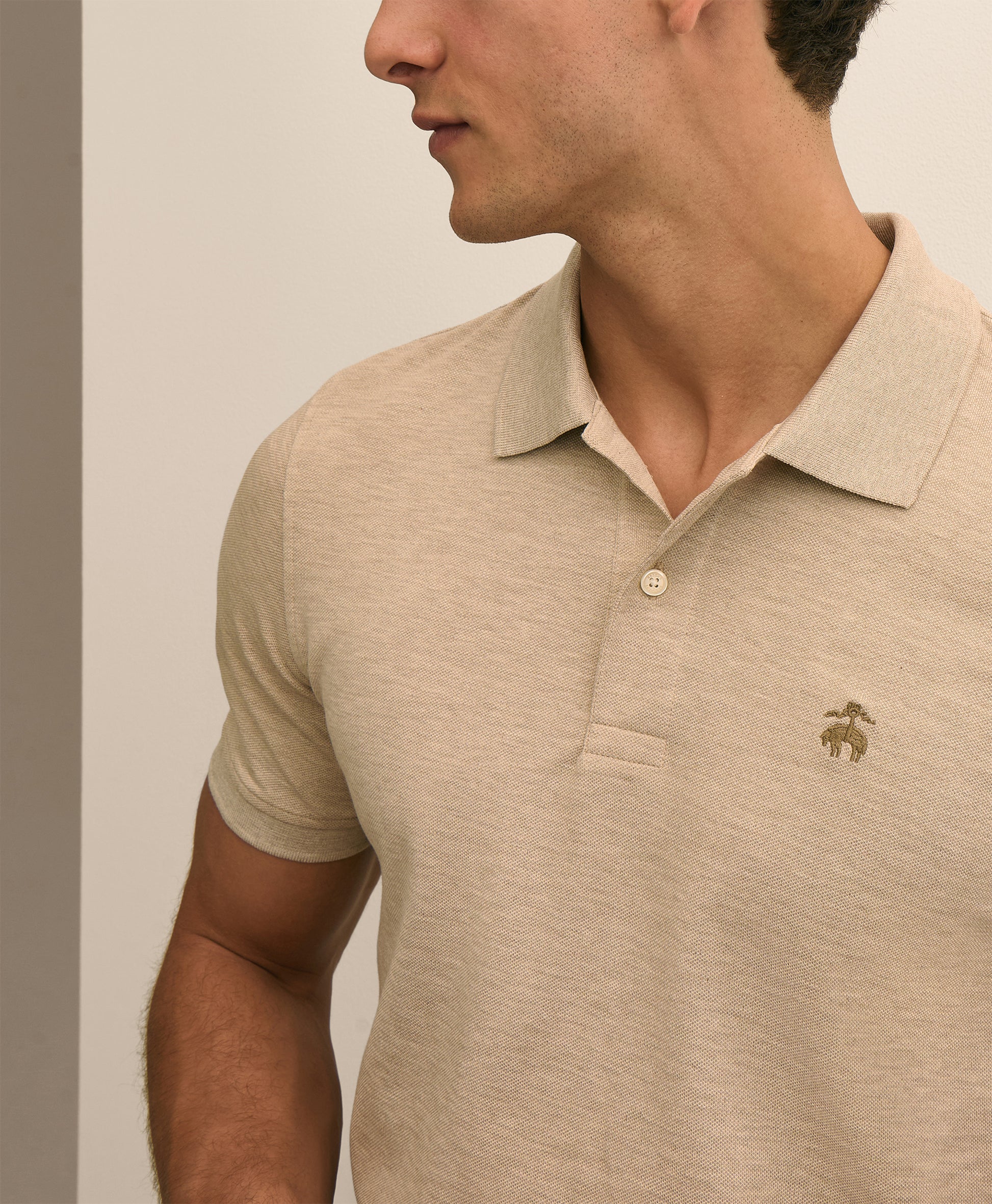Man wearing a beige polo shirt with a logo 