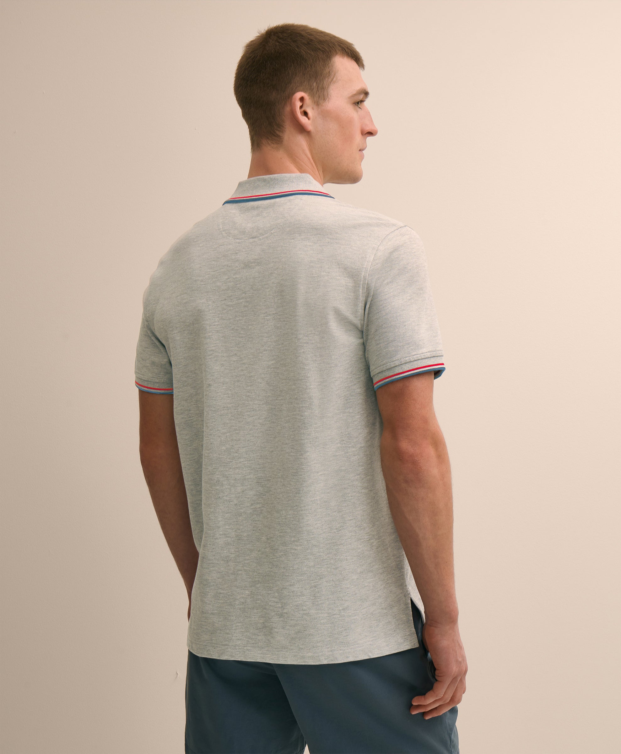 Man wearing a light gray polo shirt with striped trim