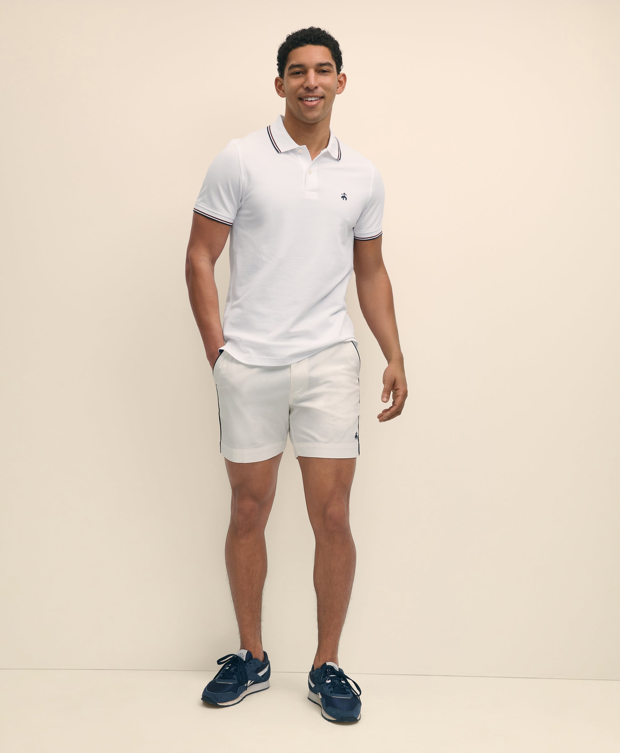 Man wearing a white polo shirt and shorts with navy shoes