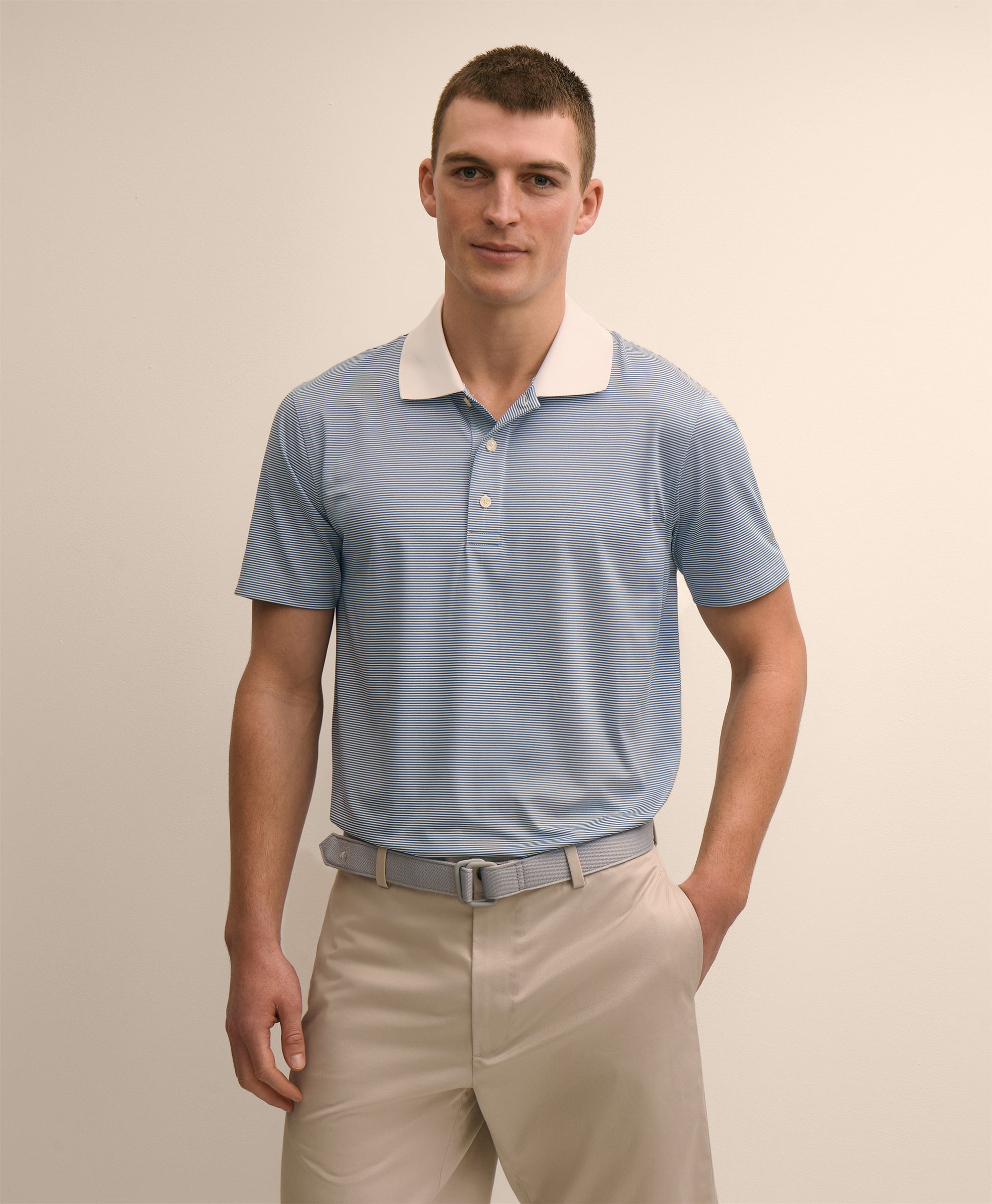 Man wearing a light blue polo shirt with a white collar and beige pants
