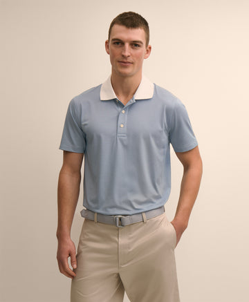 Man wearing a light blue polo shirt with a white collar and beige pants