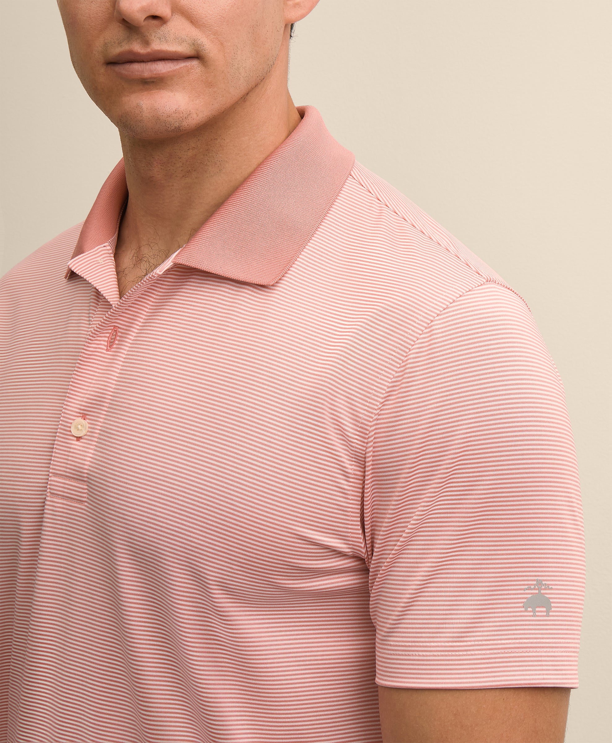 Man wearing a pink striped polo shirt with a visible brand logo