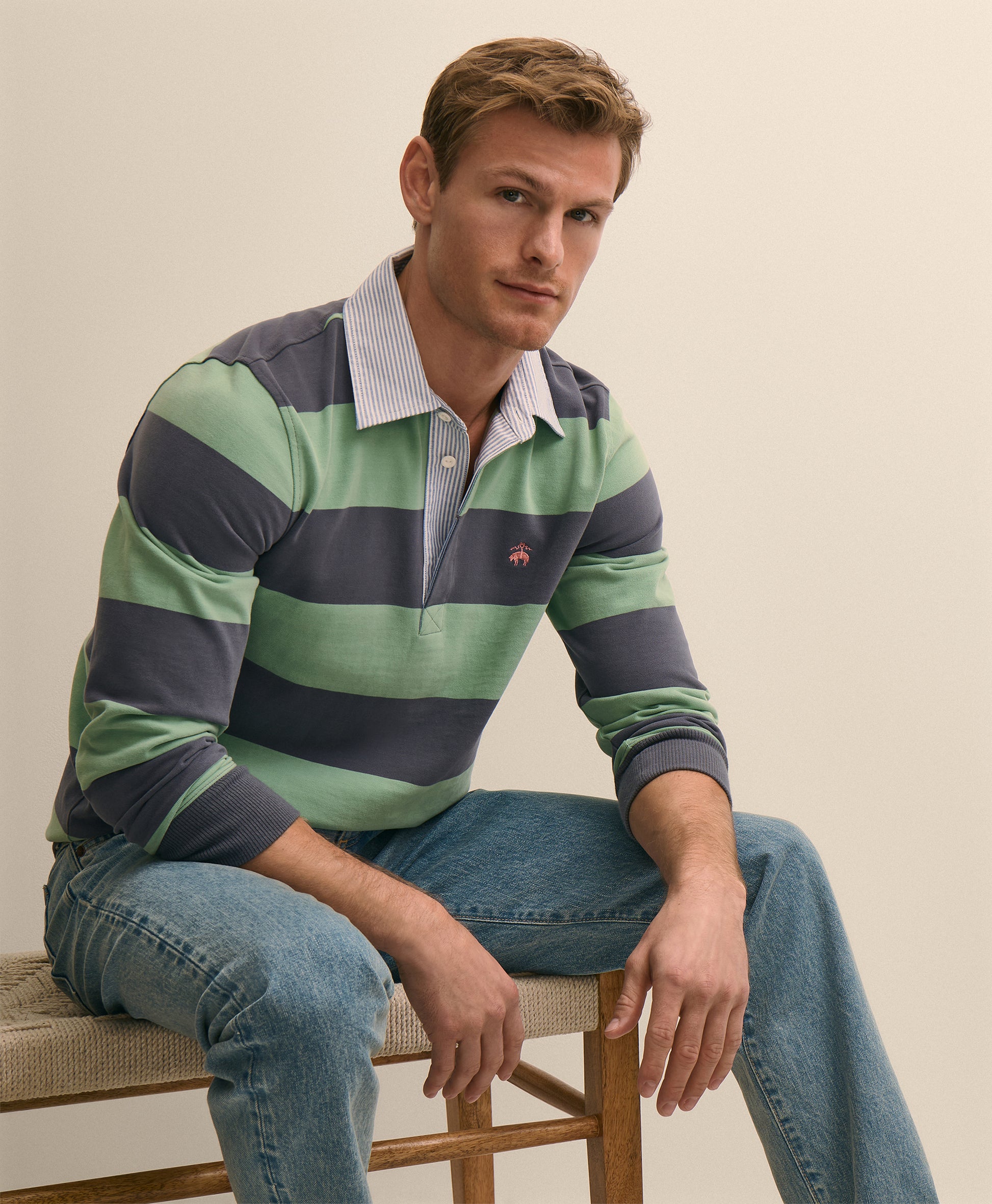 Man wearing a striped shirt and jeans sitting on a chair