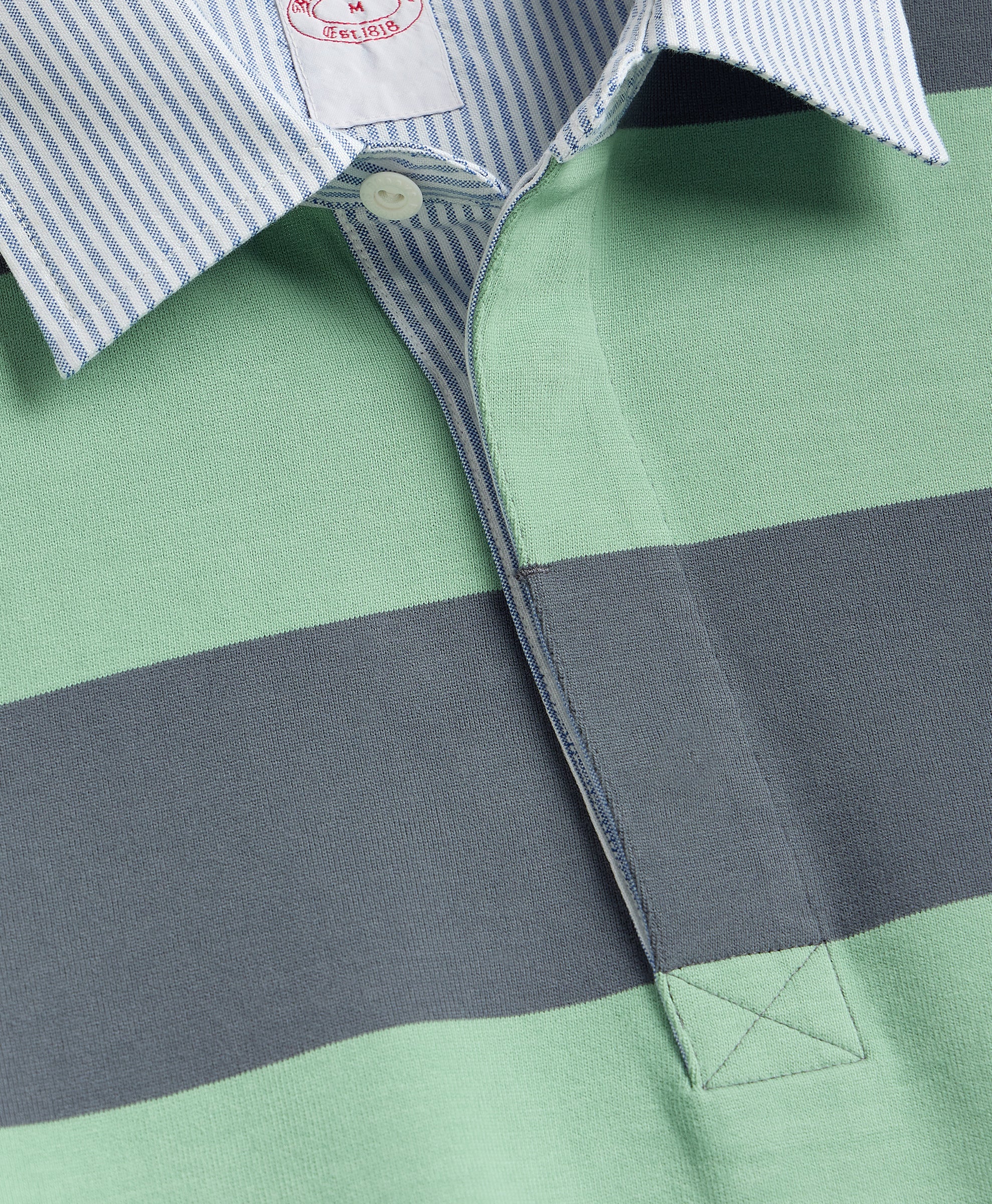 Close-up of a green and gray striped shirt with a brand label.