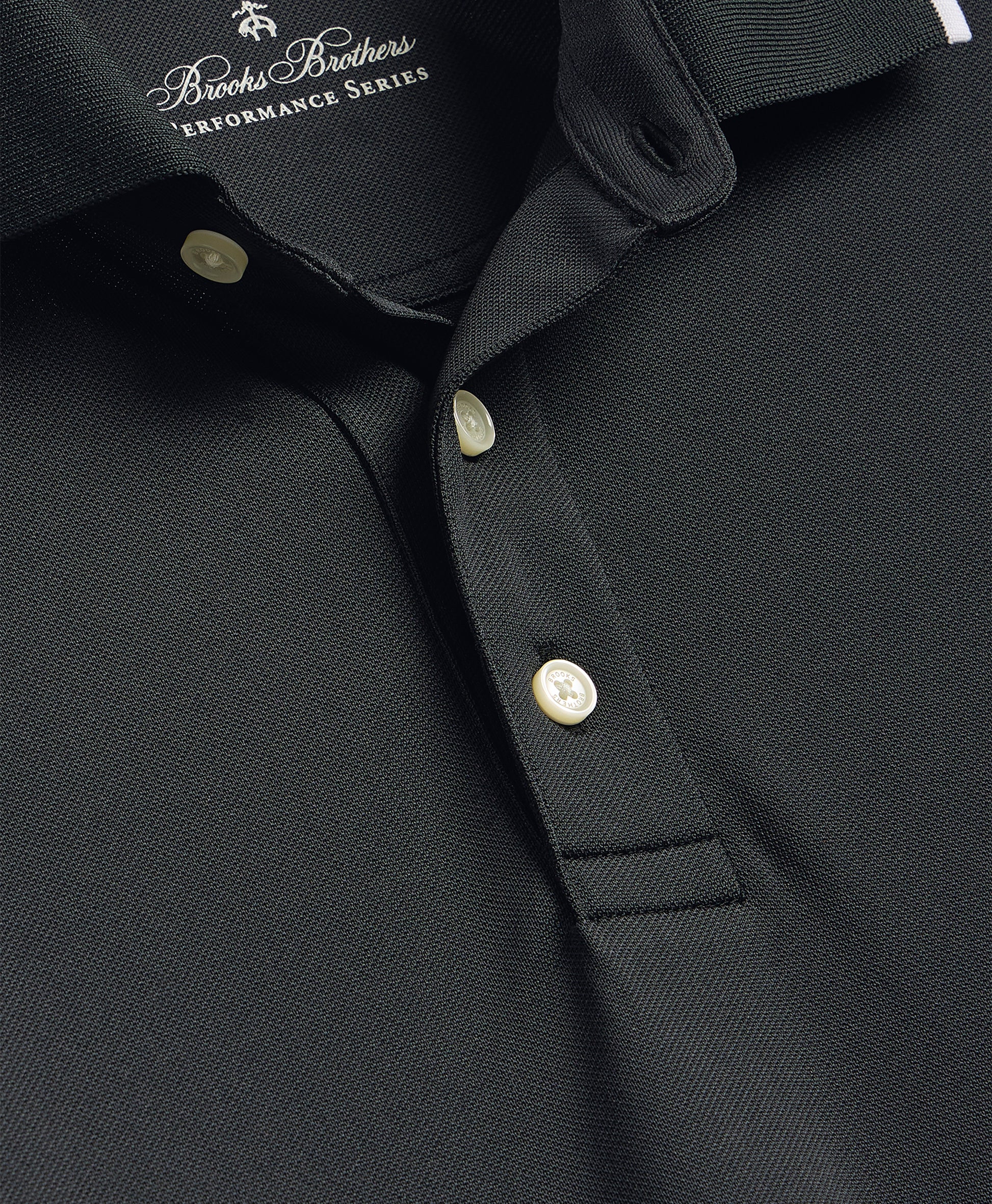Close-up of a black polo shirt with button details and Brooks Brothers logo.