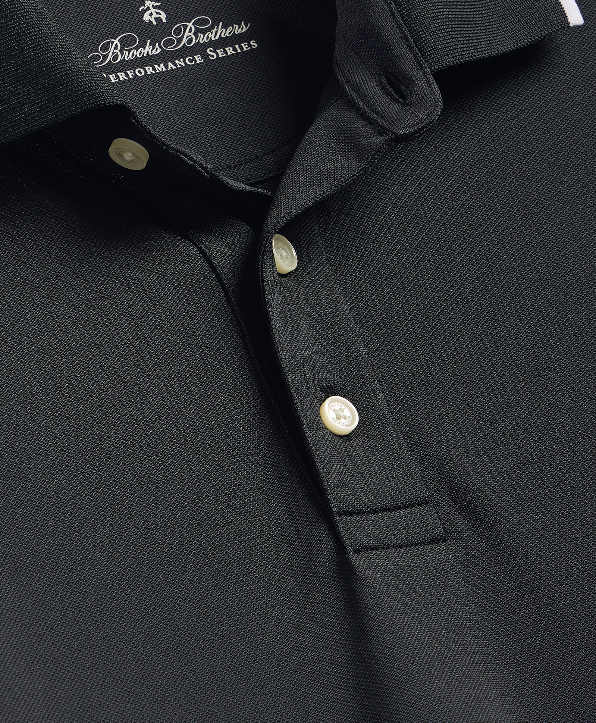 Close-up of a black polo shirt with button details and Brooks Brothers logo.