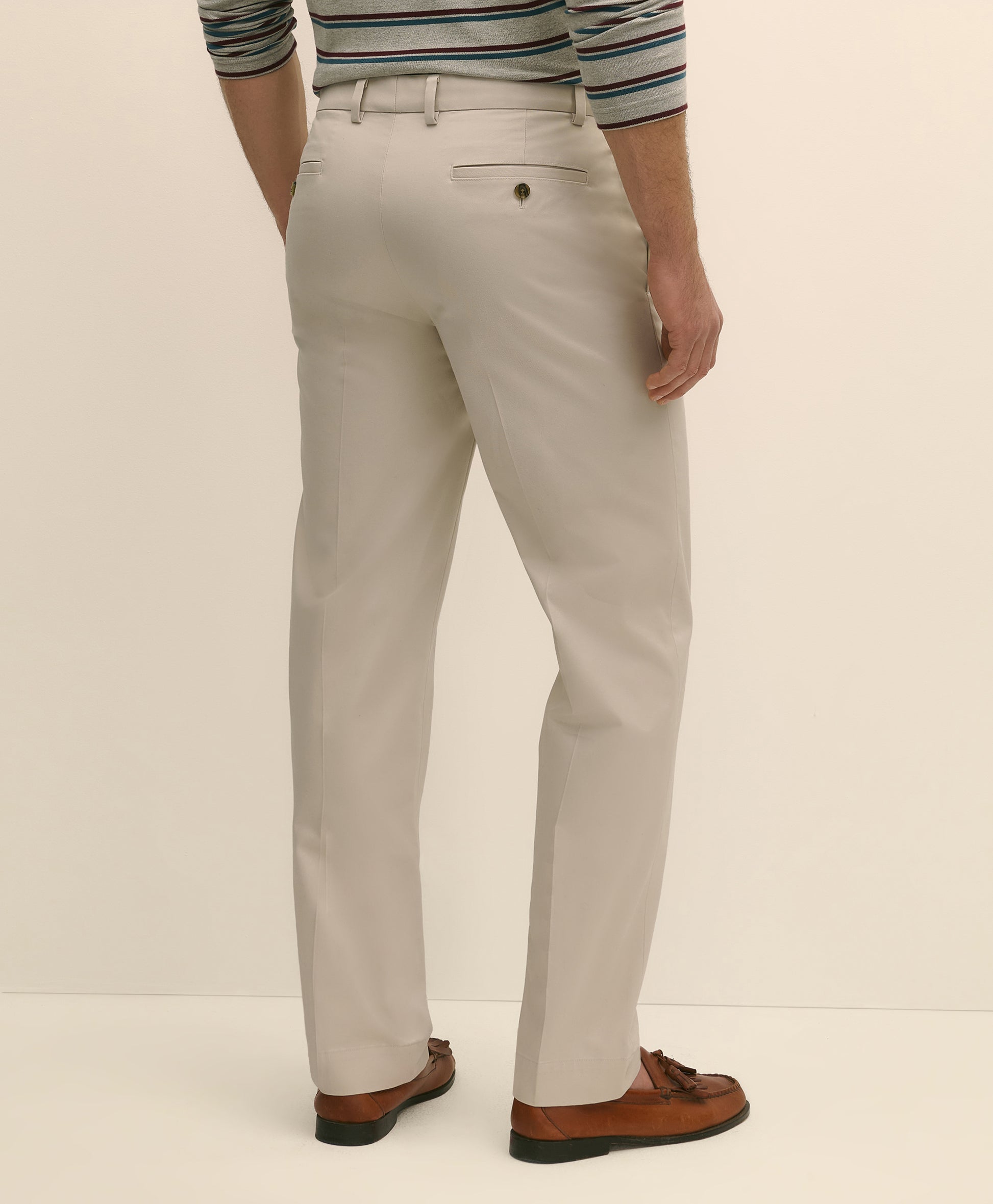 Person wearing light gray pants with a striped shirt and brown shoes