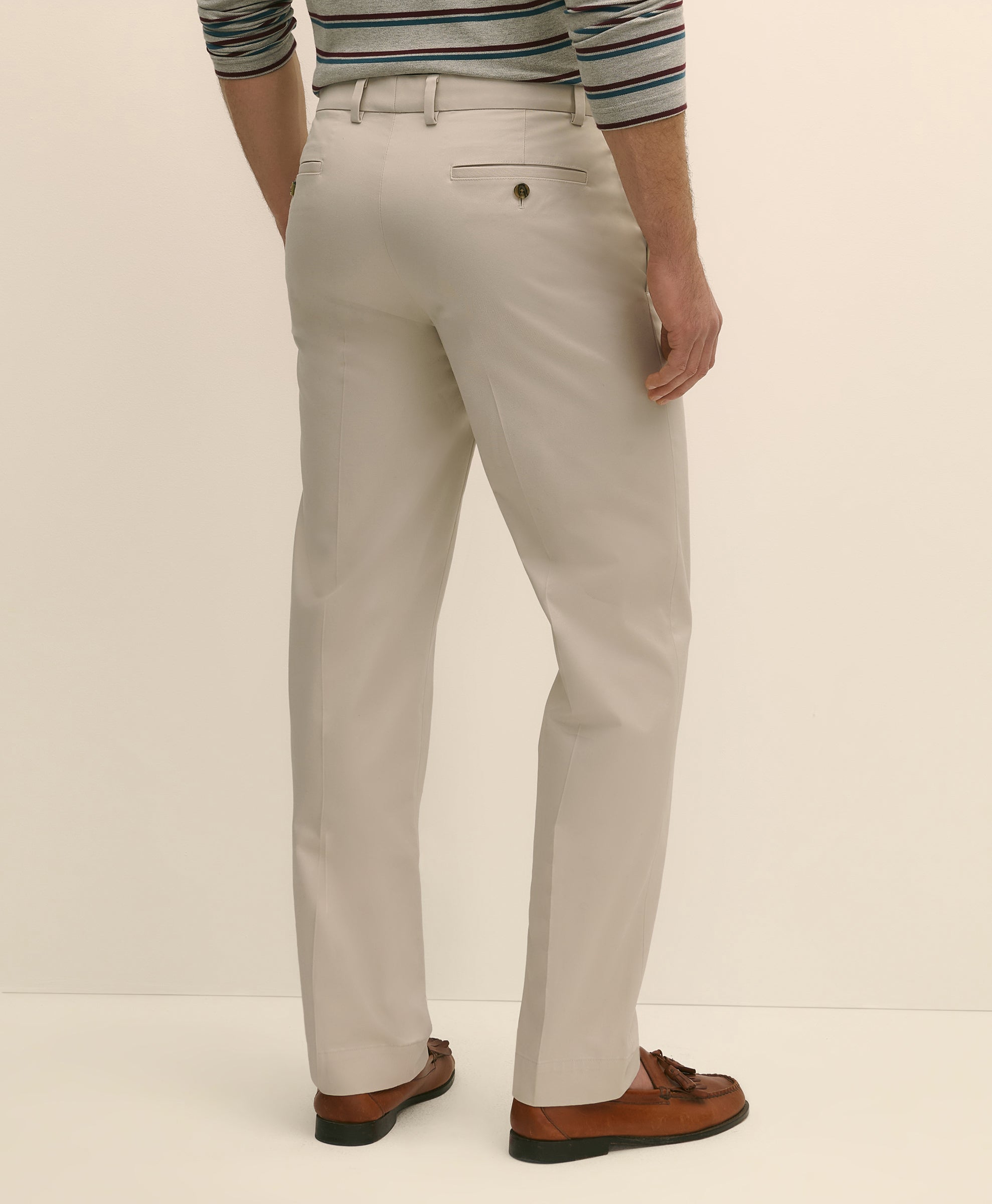 Person wearing light gray pants with a striped shirt and brown shoes