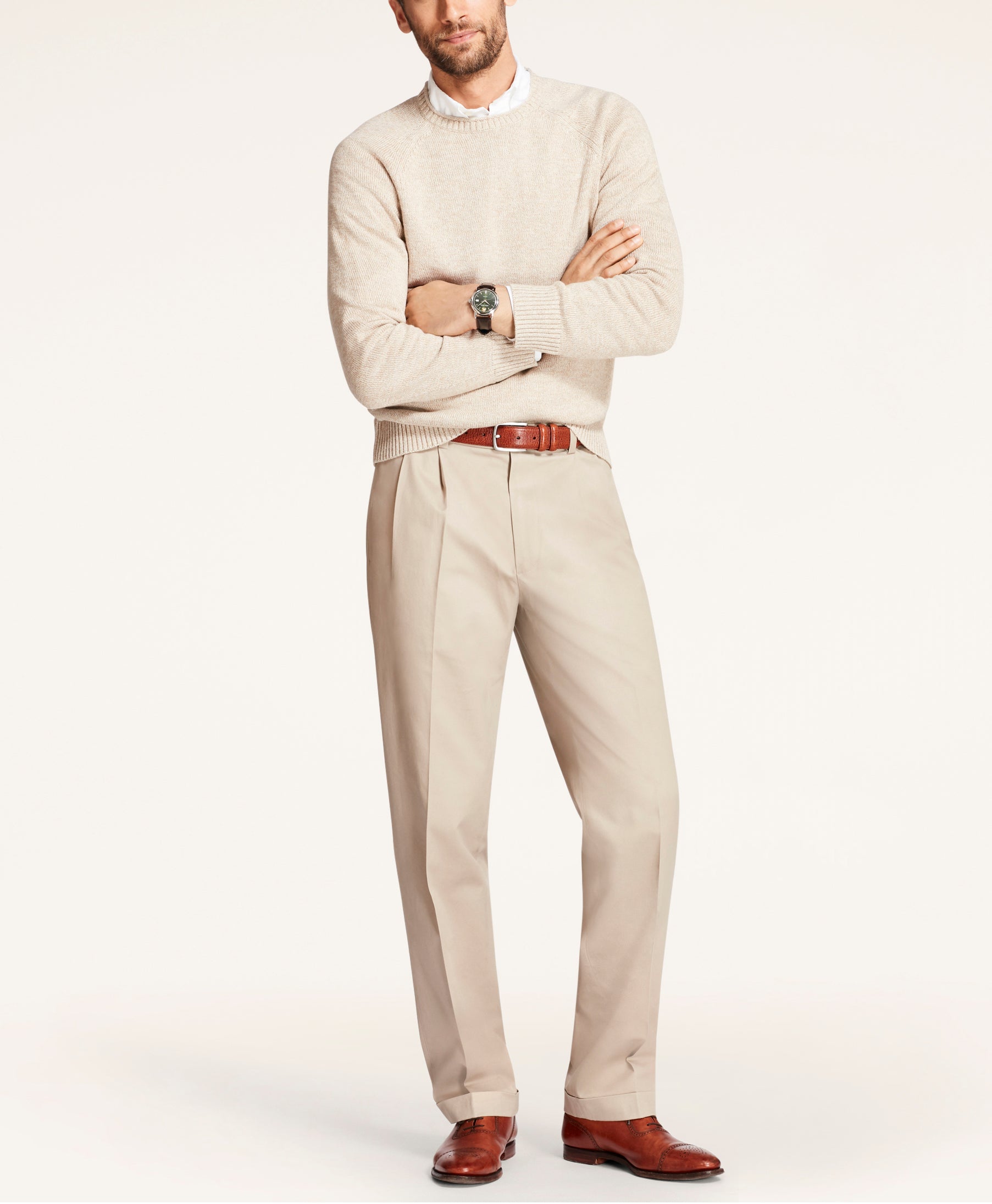 Man wearing a beige sweater and pants with a white shirt underneath