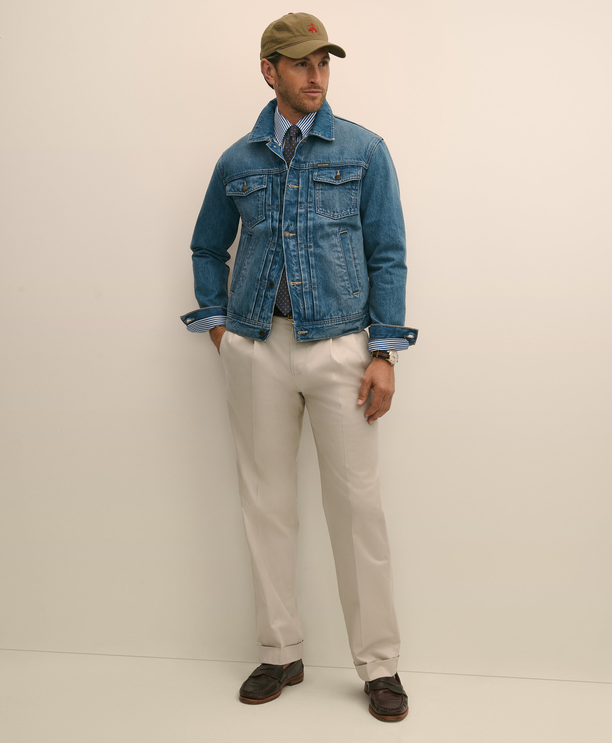 Man wearing a denim jacket, beige cap, and light-colored pants