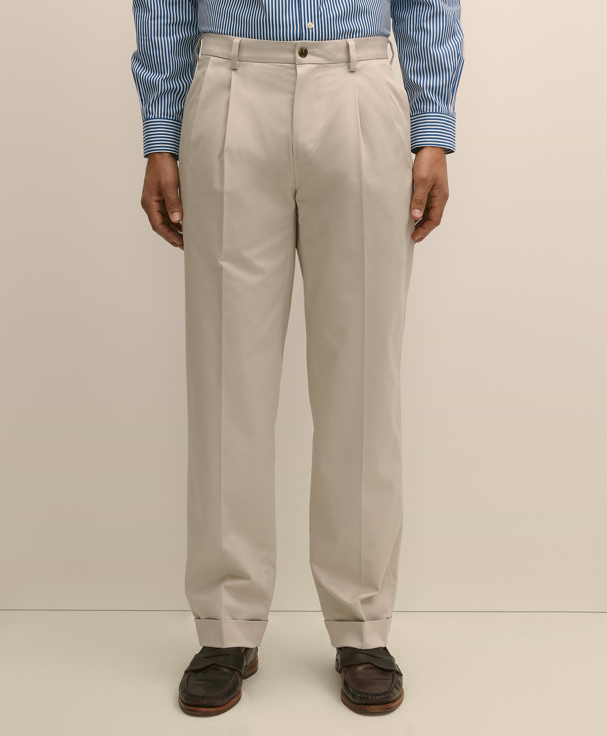 Person wearing beige dress pants with a blue striped shirt