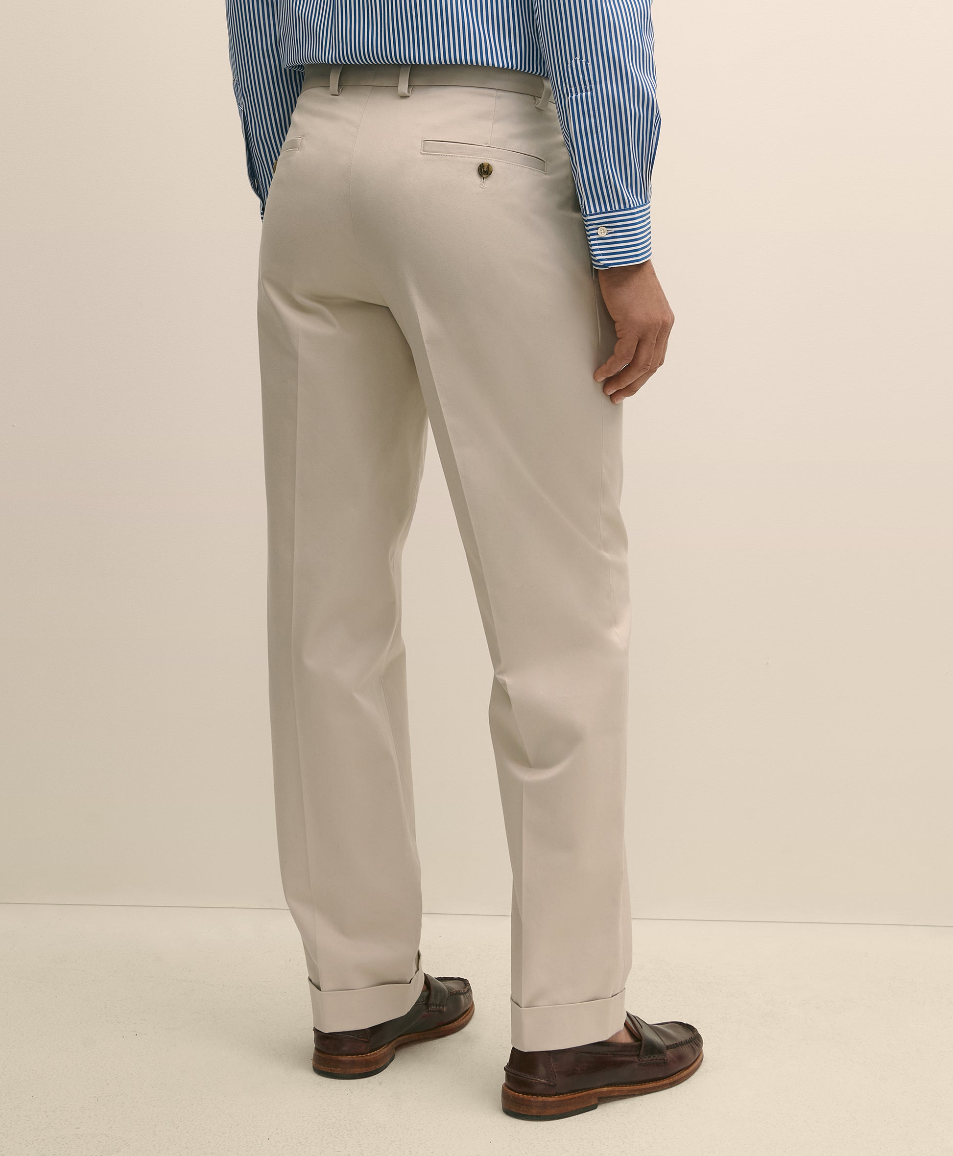 Person wearing beige dress pants with a blue striped shirt
