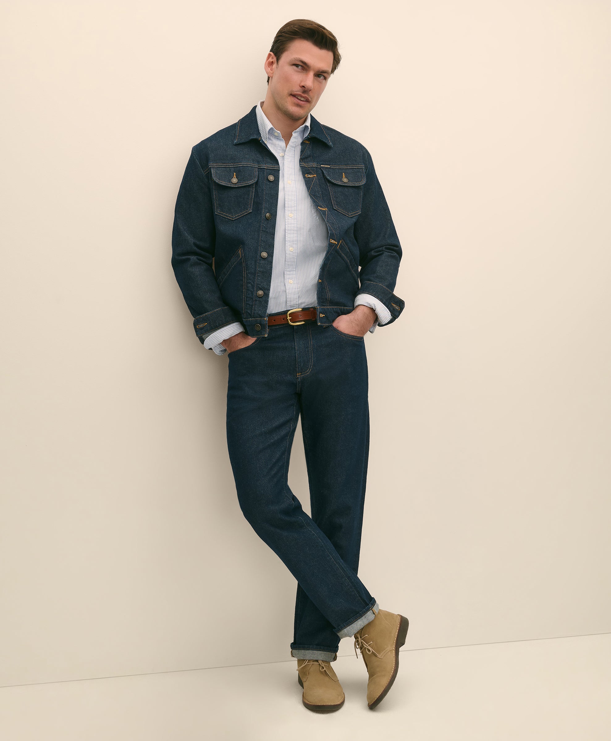 Man wearing a denim jacket, white shirt, dark jeans, and brown boots