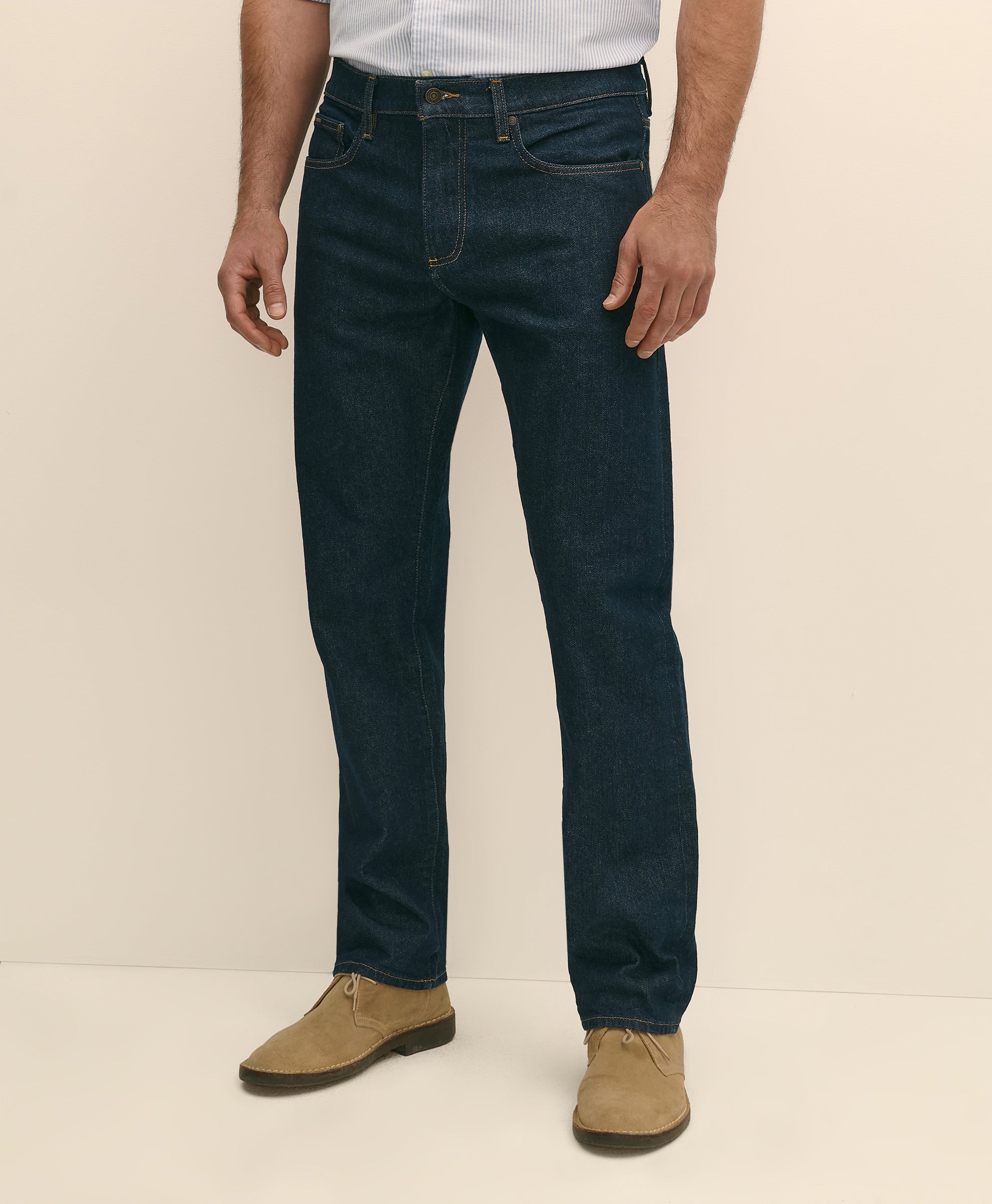 Person wearing dark blue jeans and tan shoes