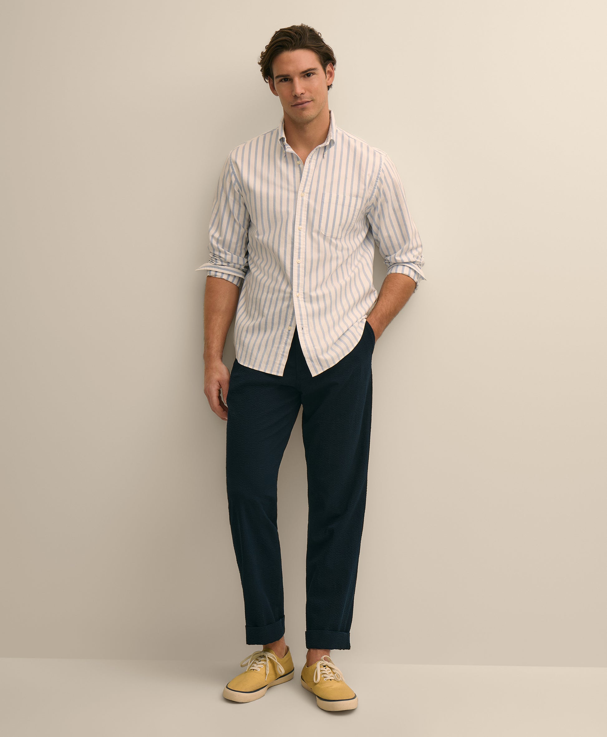 Man wearing a striped shirt, navy pants, and tan shoes