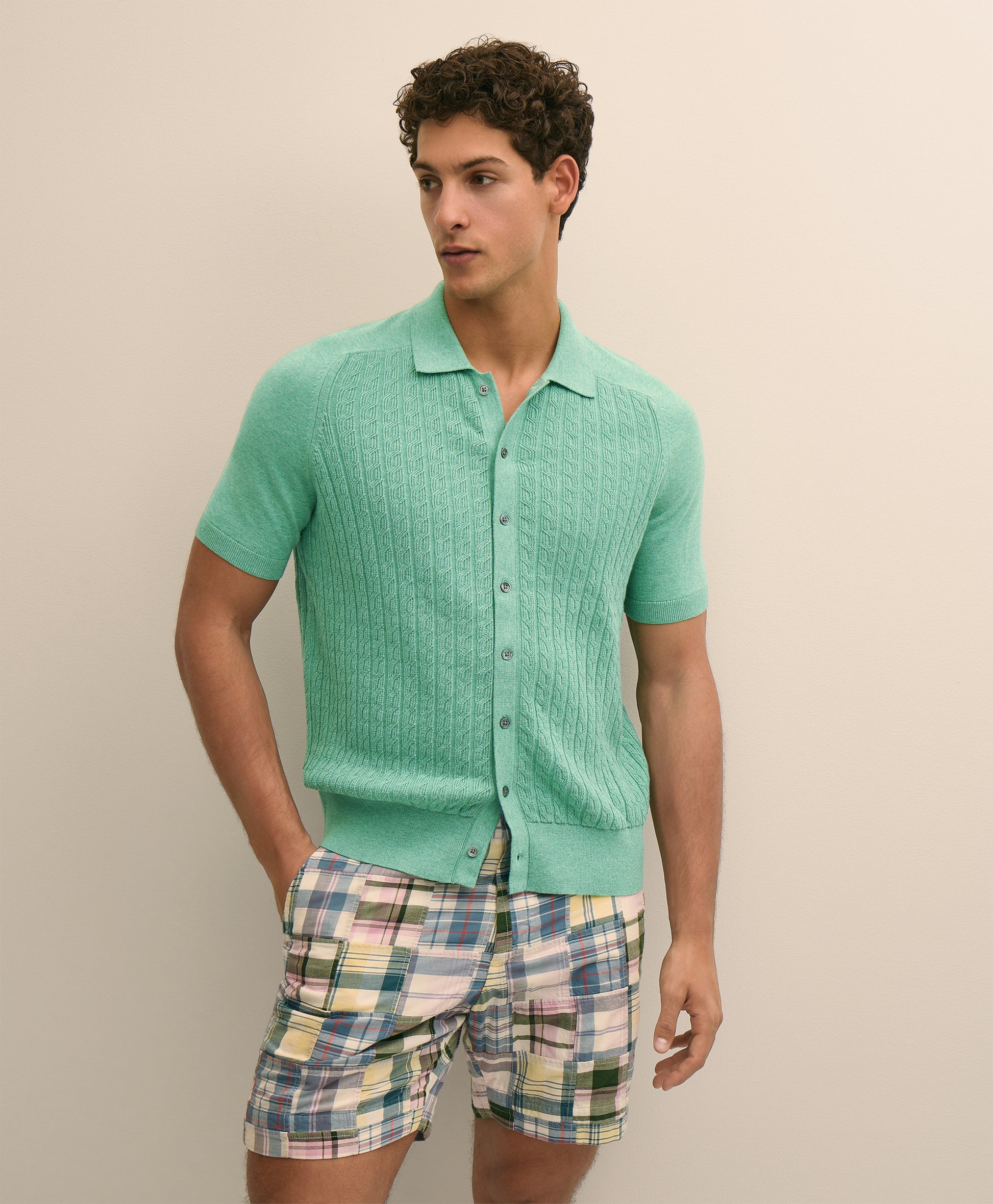 Man wearing a green textured shirt and plaid shorts