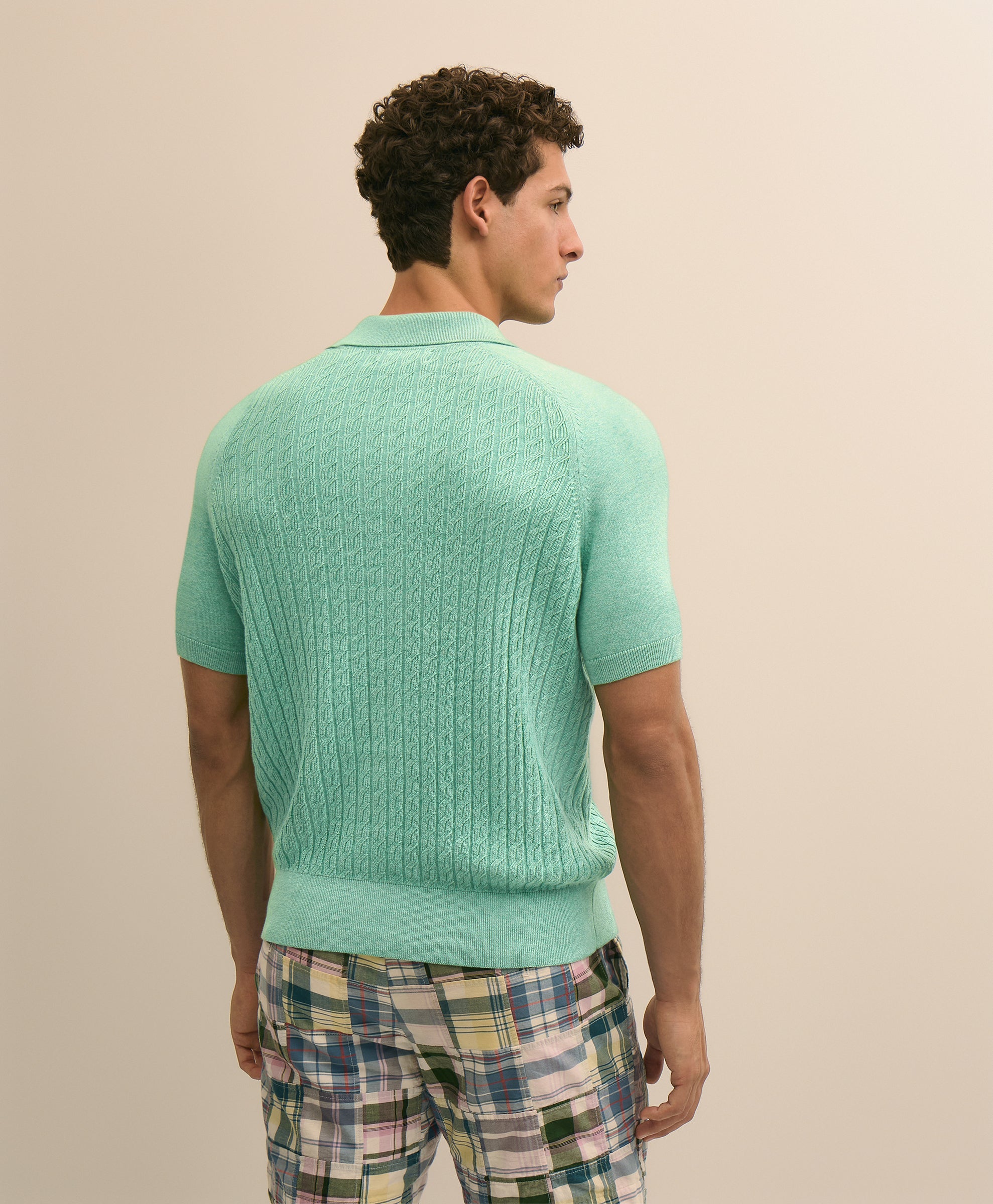 Man wearing a light green sweater and plaid pants