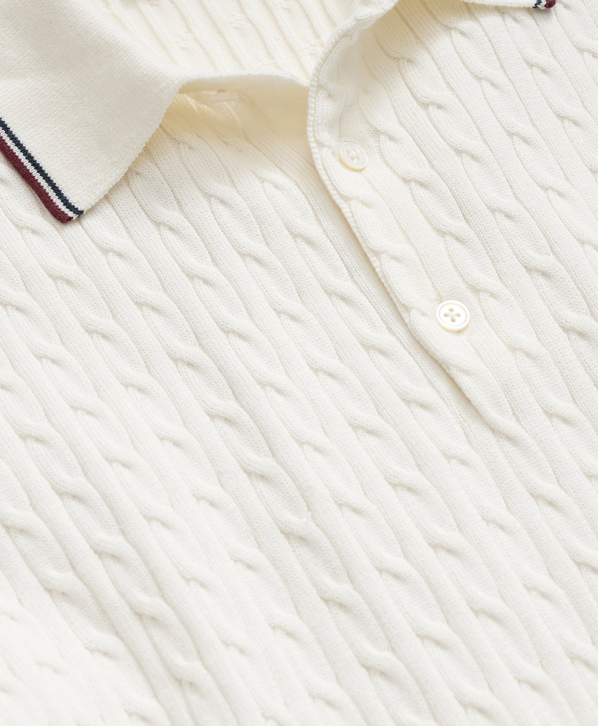 Close-up of a textured white shirt with a collar and button details.