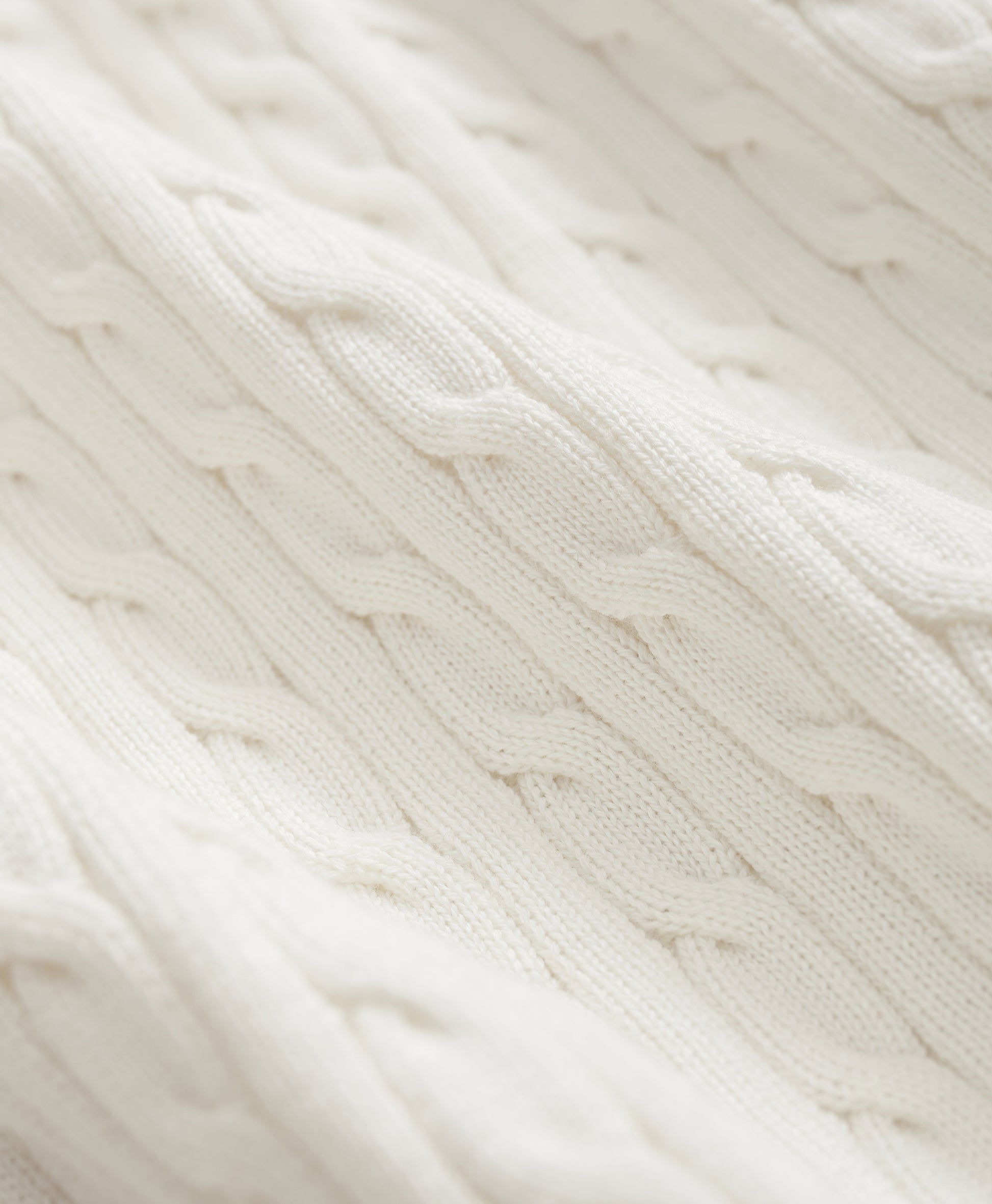 Close-up of a white knitted fabric with cable pattern