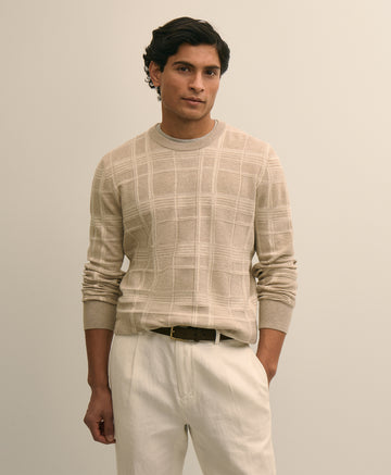 Man wearing a beige checkered sweater and white pants