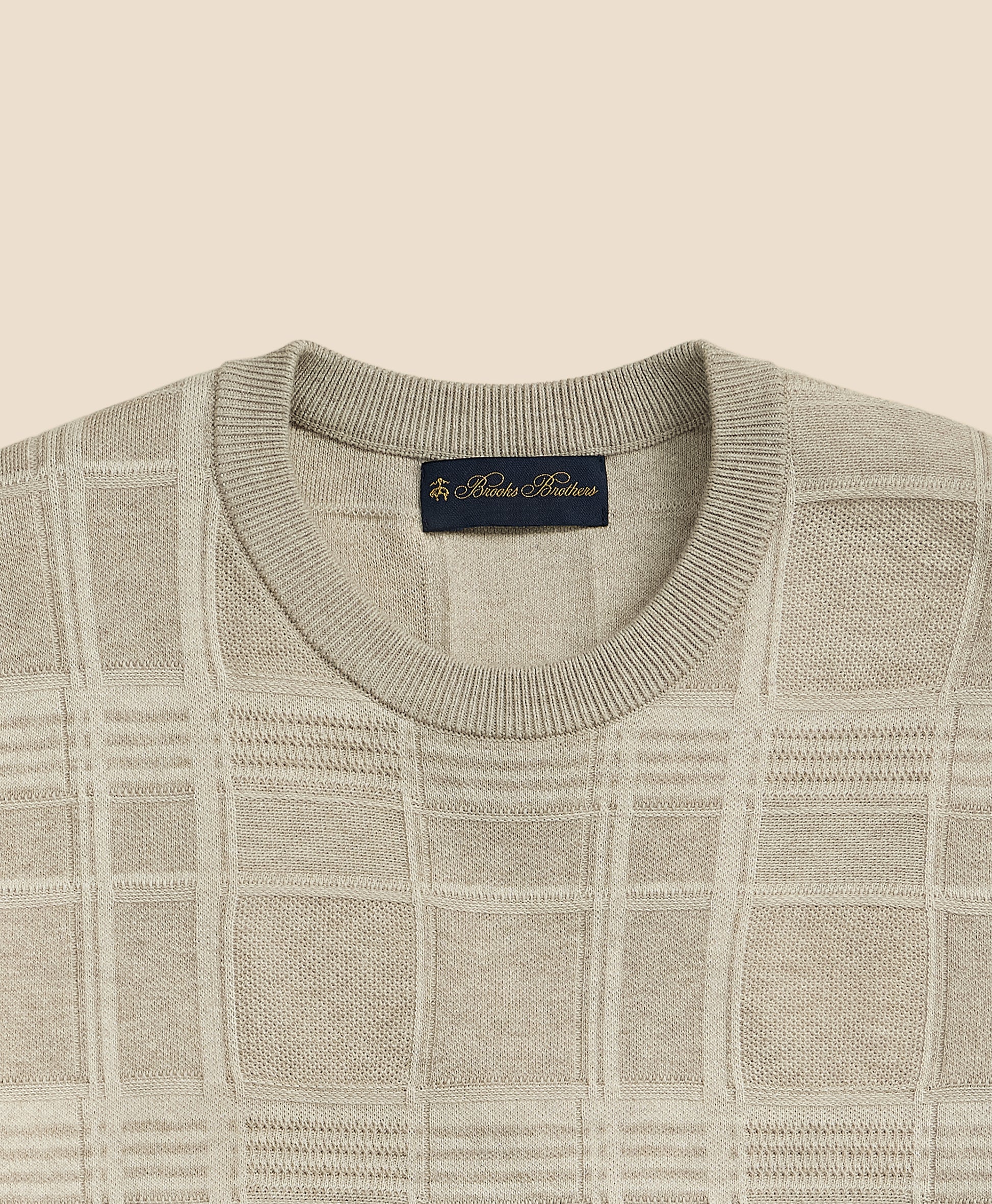 Close-up of a gray checkered sweater with a brand label