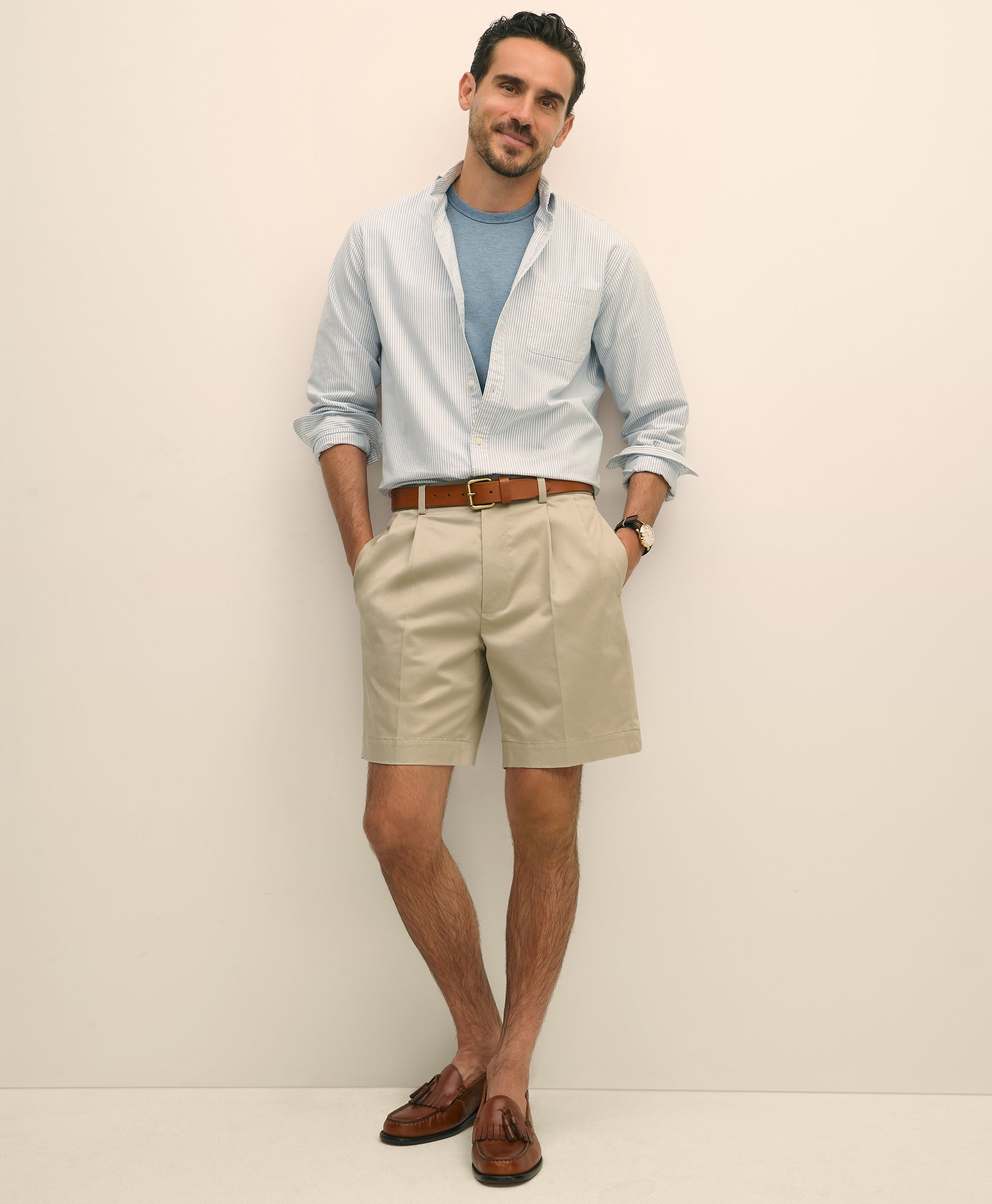 Man wearing a light blue shirt, beige shorts, and brown shoes